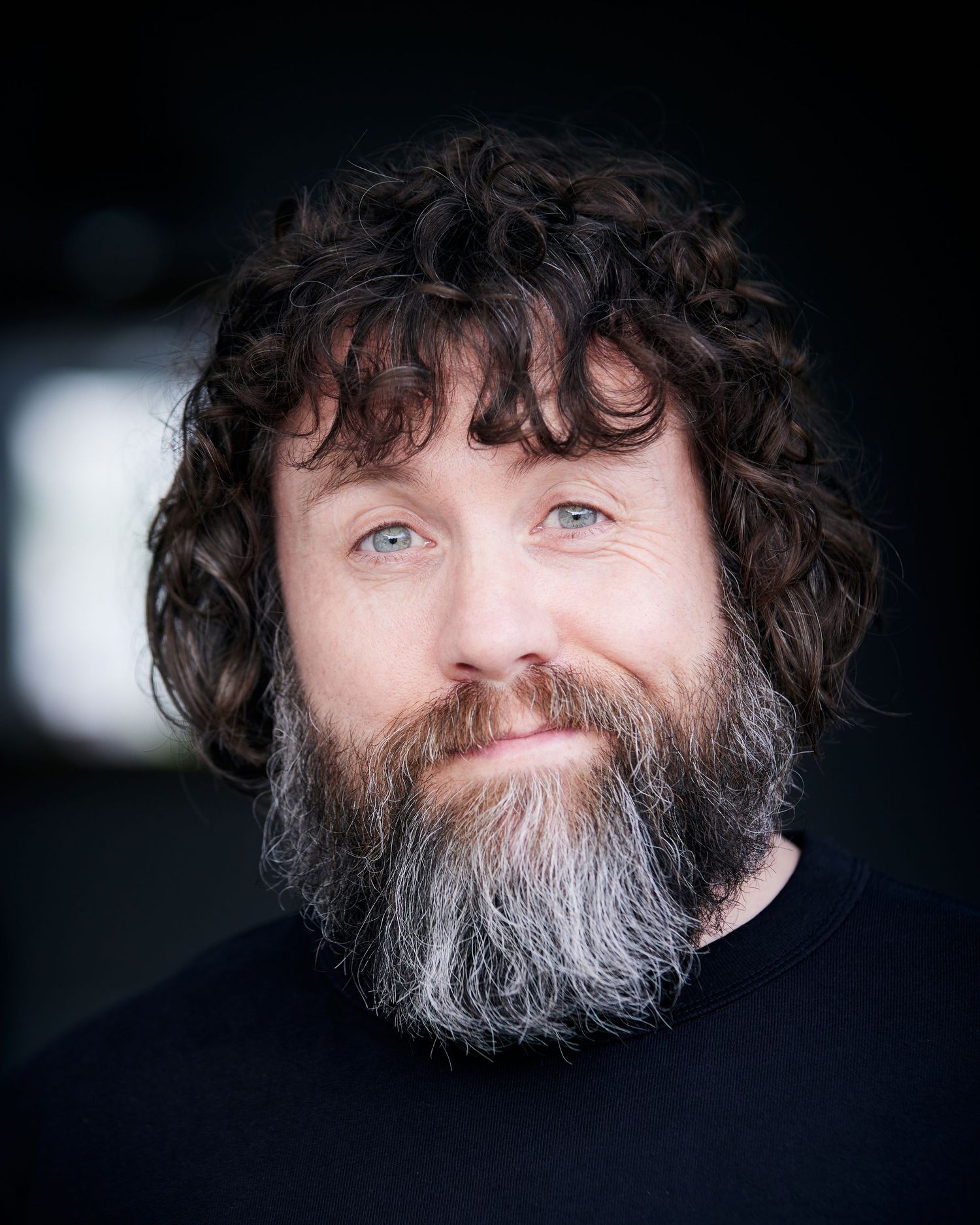 Cheerful character portrait; comedic look with soft-lit background.