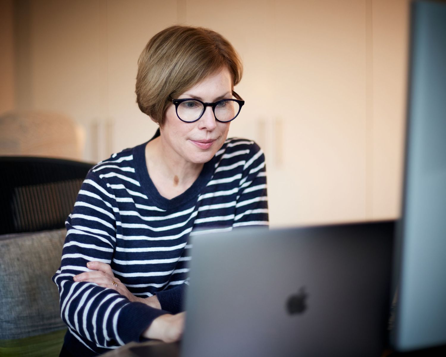 Creative businesswoman in Cardiff; focused on her laptop with a coffee, natural light, and soft bokeh background.