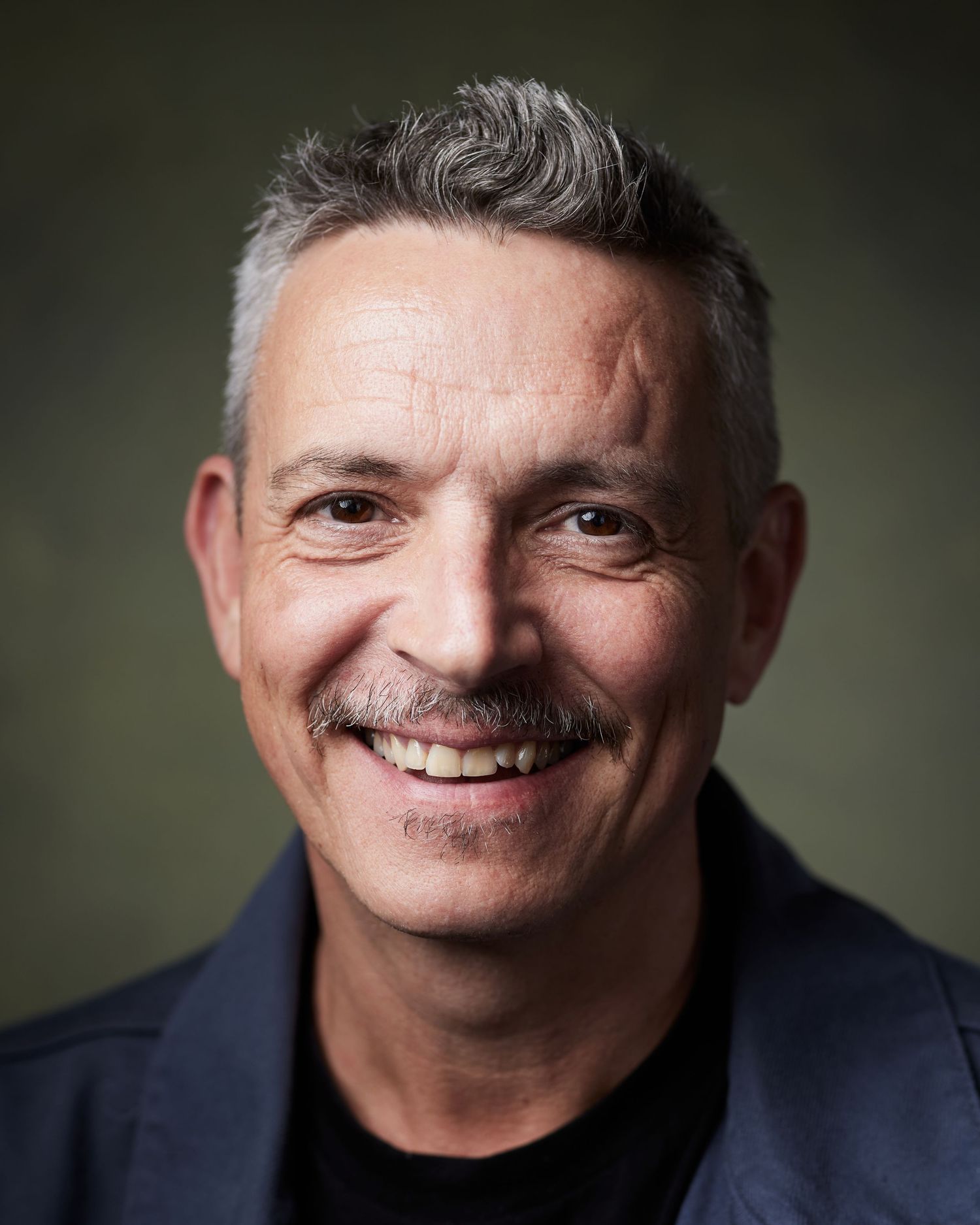 Cheerful actor headshot with a charismatic smile against a green canvas backdrop.