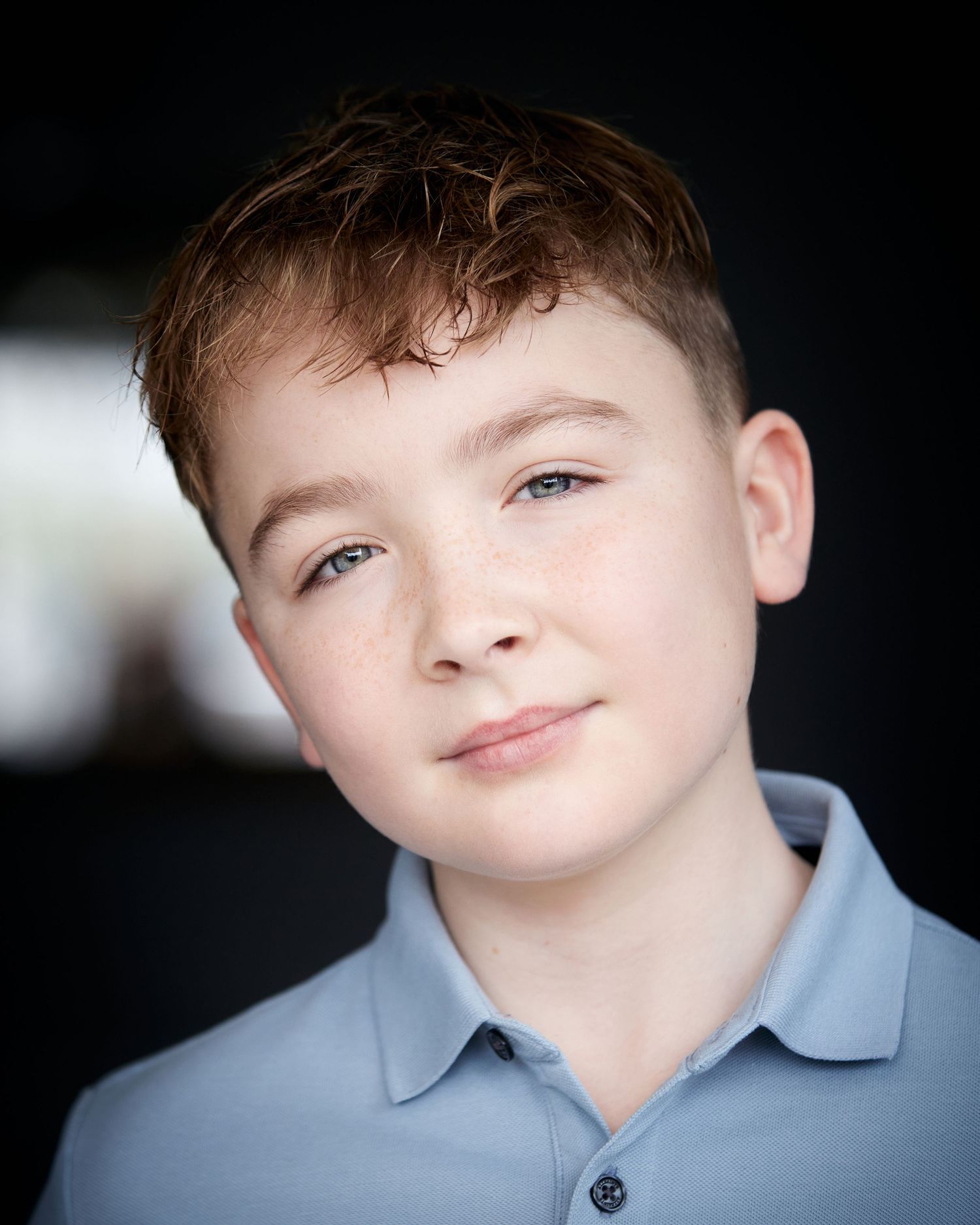 Approachable natural light headshot; young actor with an approachable soft smile and soft background.