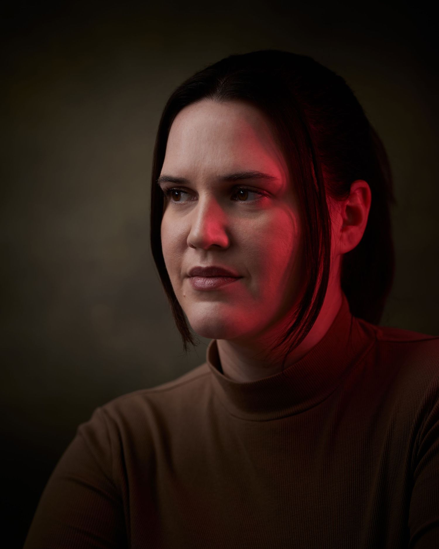 Low-key studio portrait; female actor looking off-camera and cinematic lighting.