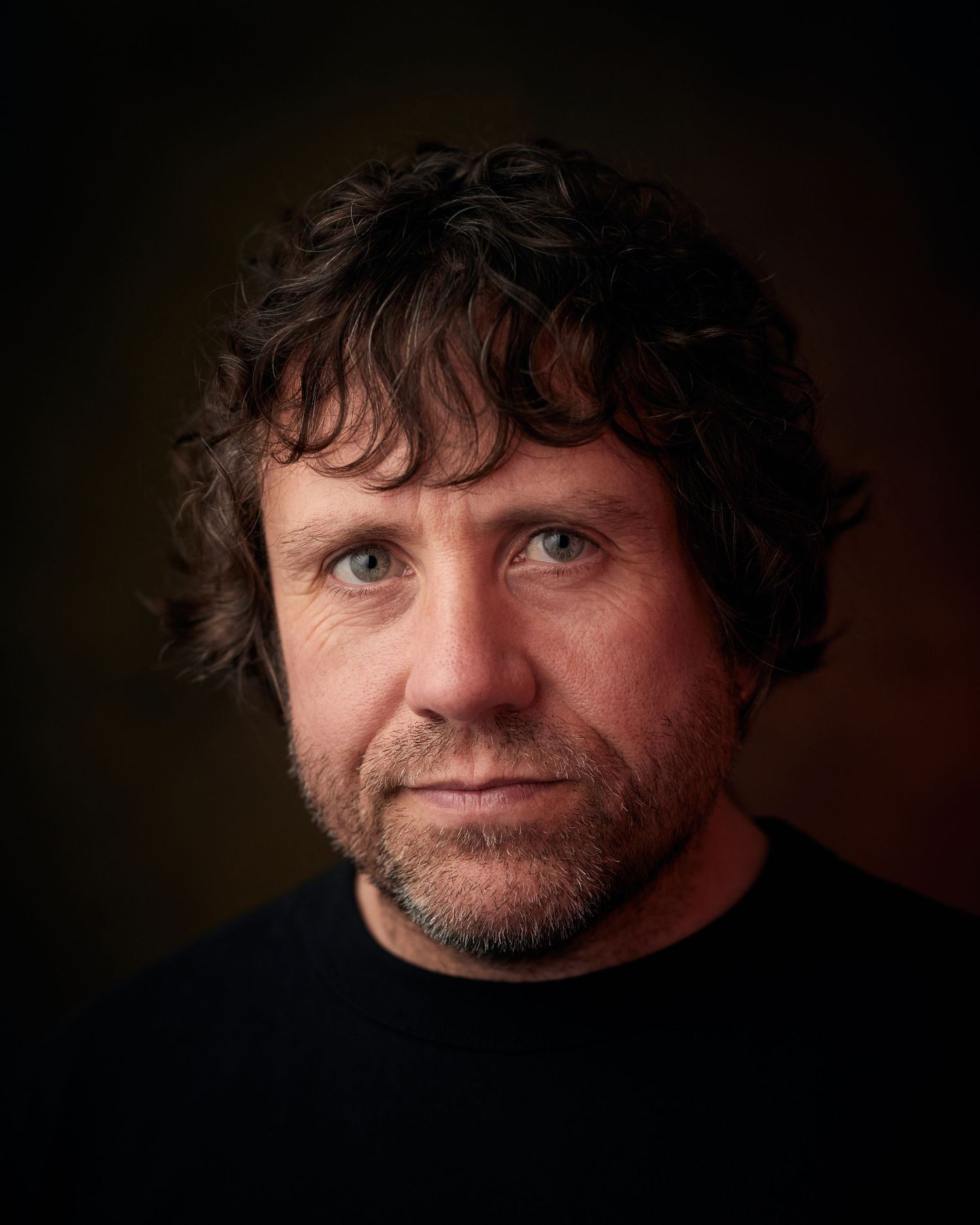 Serious actor headshot; man with a deep, thinking expression and low key lighting.