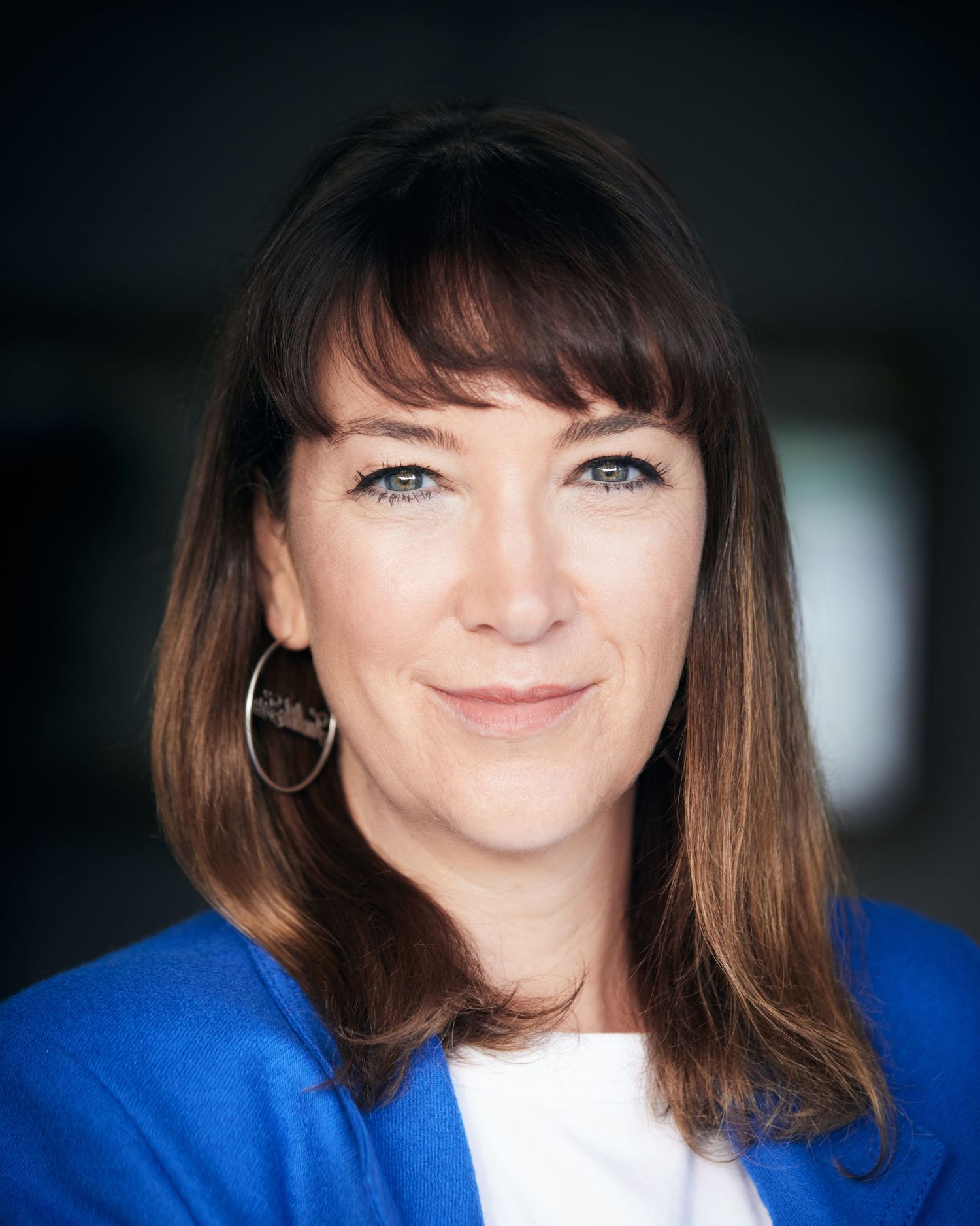 Professional business headshot by Director Geraint Todd; woman in a cobalt blue blazer with a welcoming, confident smile and dark fringe.