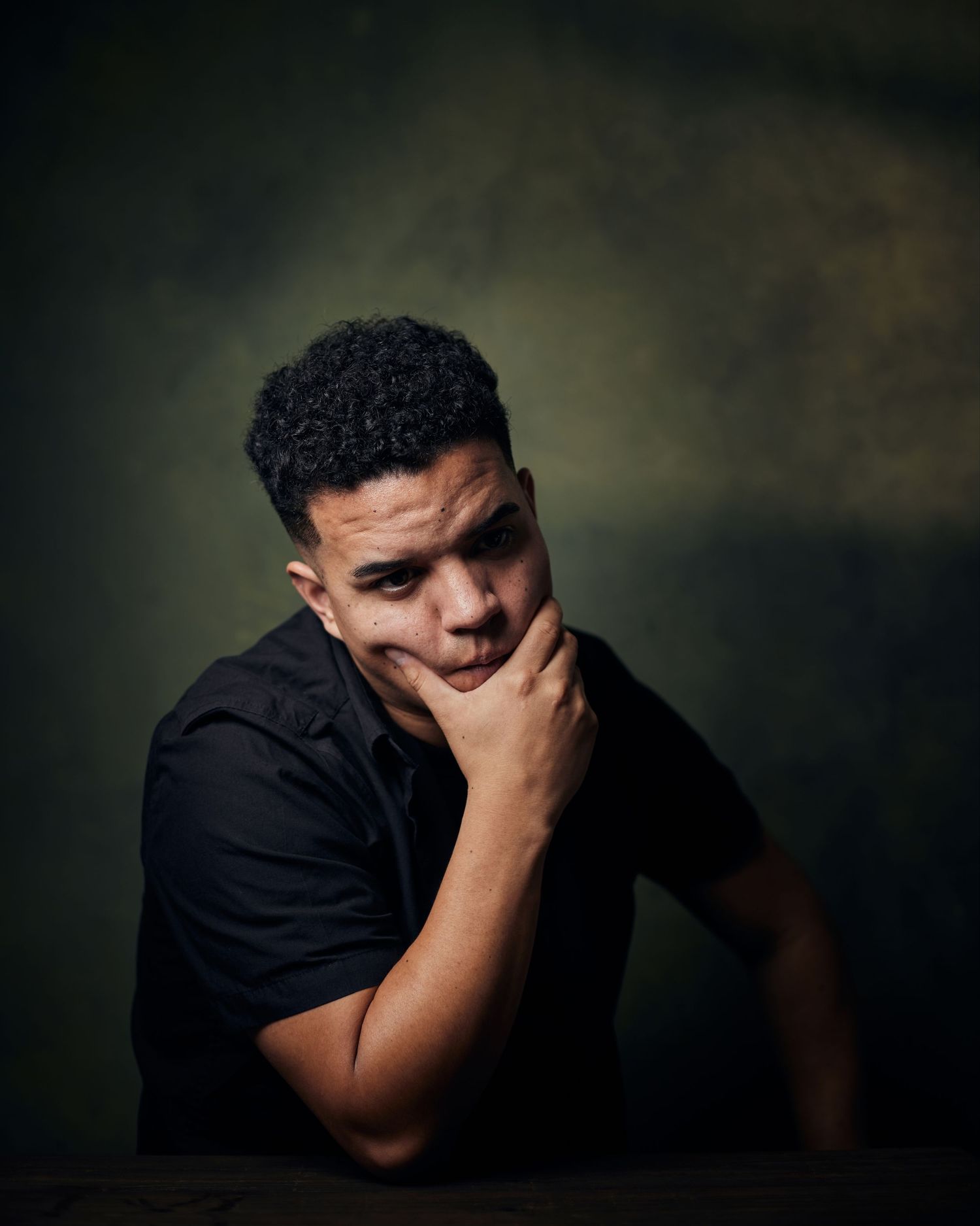 Cinematic headshot; actor with a heavy, contemplative and threatening energy and dark shadows.