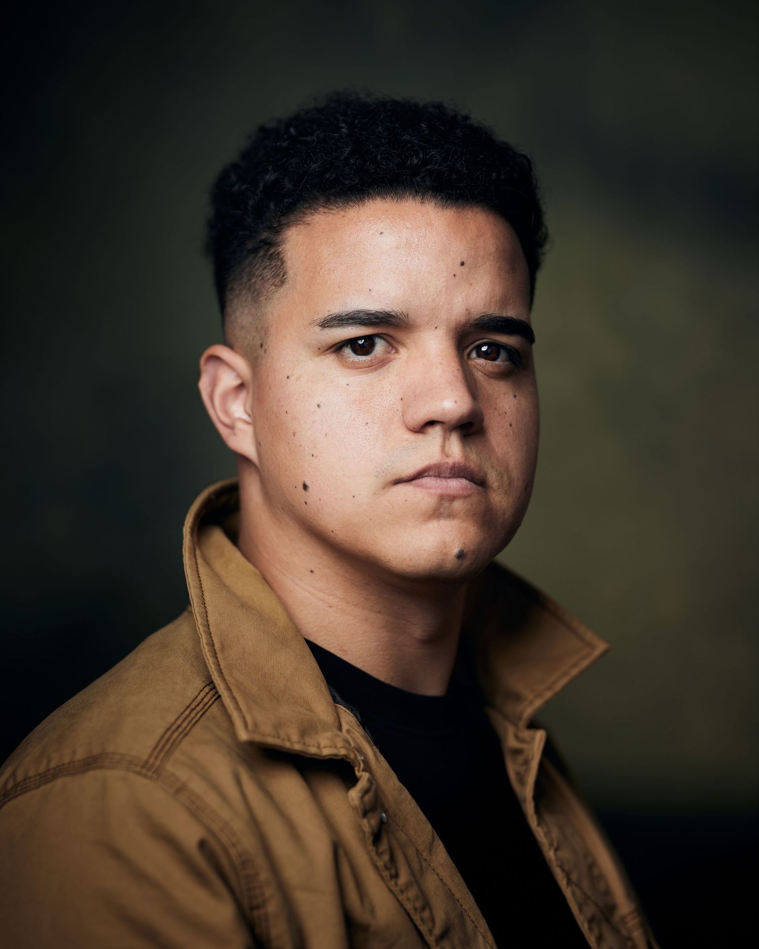 Intense actor headshot; male performer with a focused, unwavering look and cinematic light.
