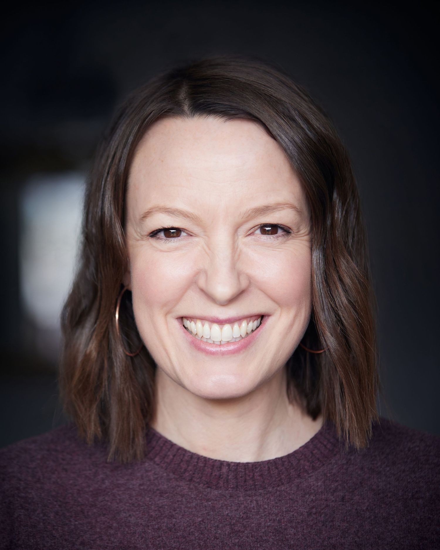 Warm approachable headshot; actress with a big smile and friendly look.