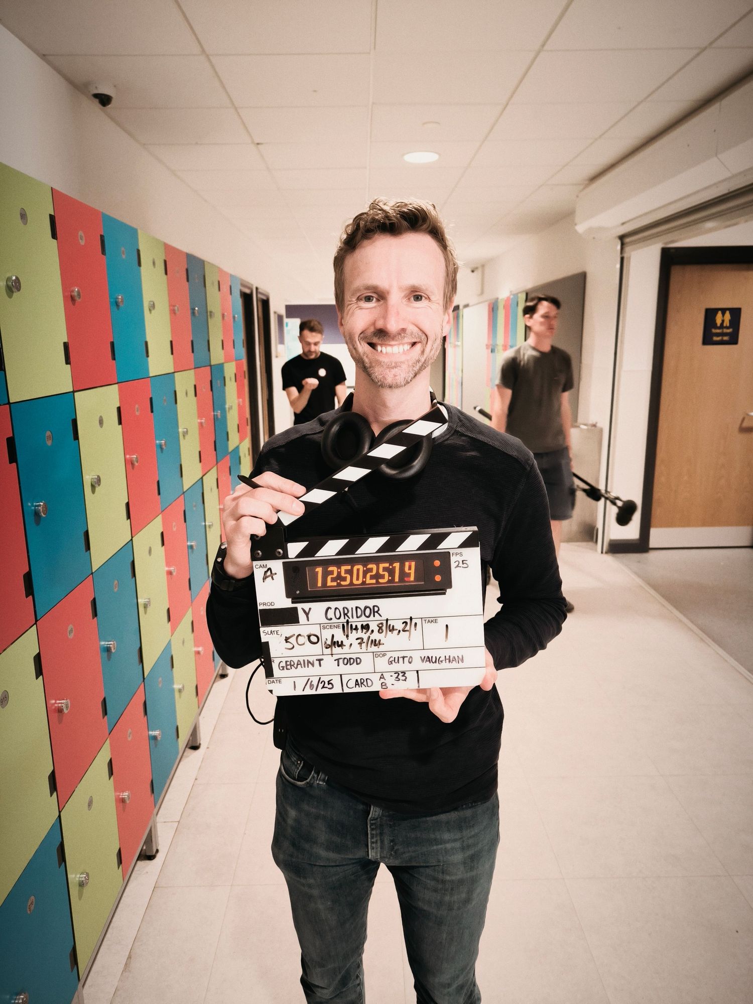 Film director Geraint Todd on set holding a cinematic clapper board.