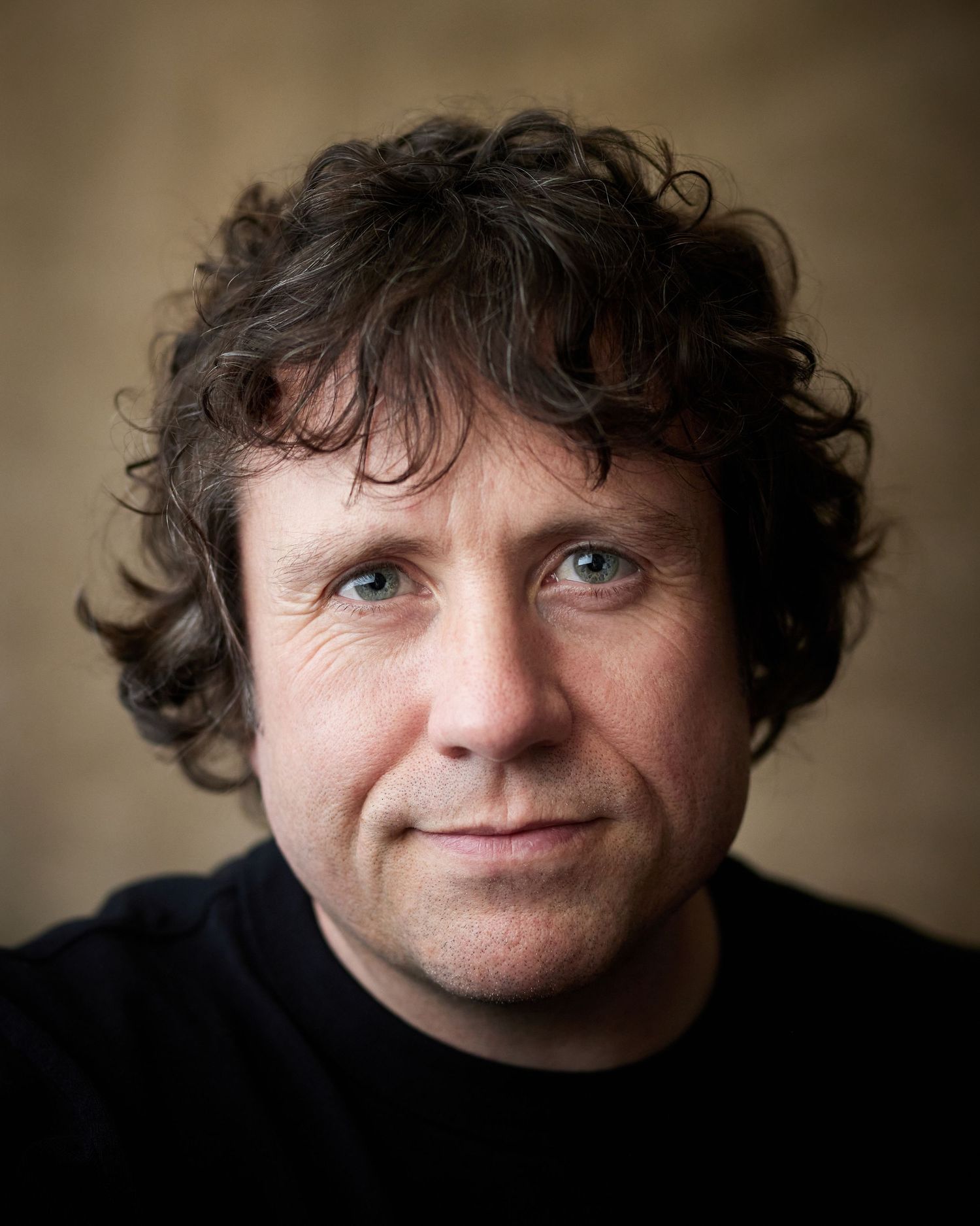 Genuine warm headshot; male performer with a kind and gentle gaze.