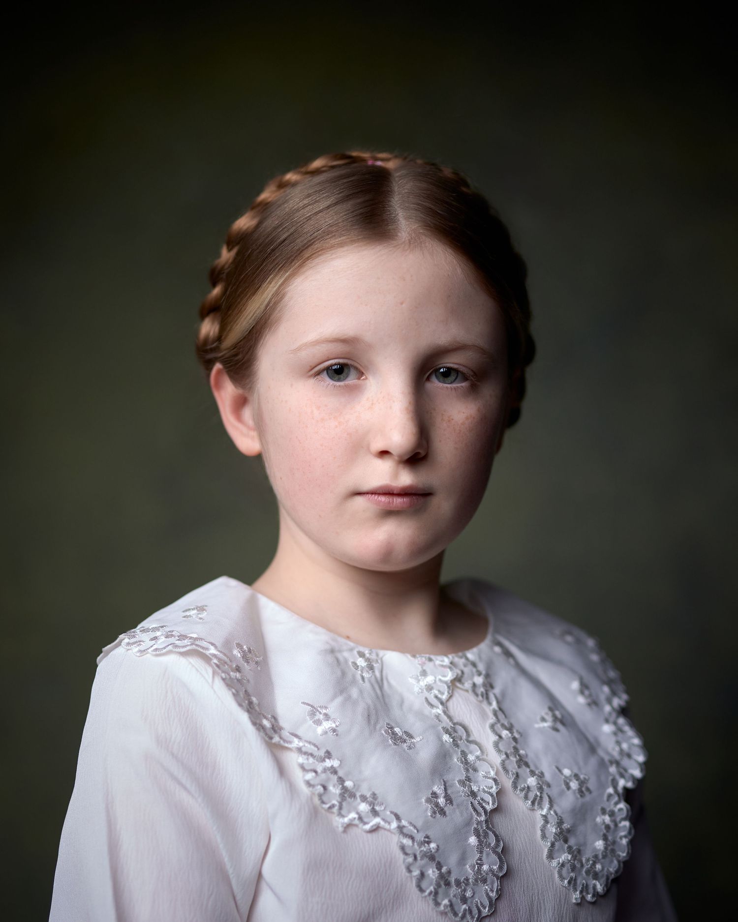 Child actor headshot in period style. Braided hair, lace collar, moody lighting. Serious, cinematic expression for period drama casting.
