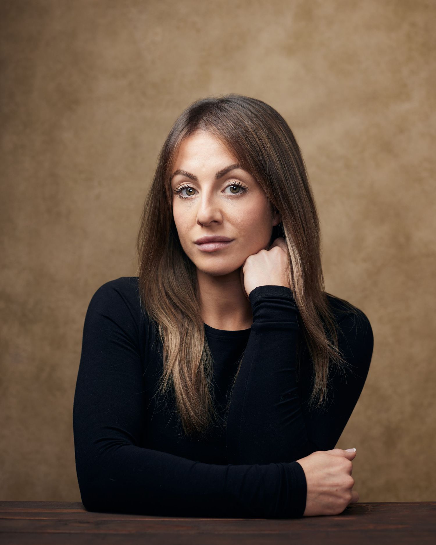 Edgy headshot; woman with a mysterious, guarded look against a brwon textured background.