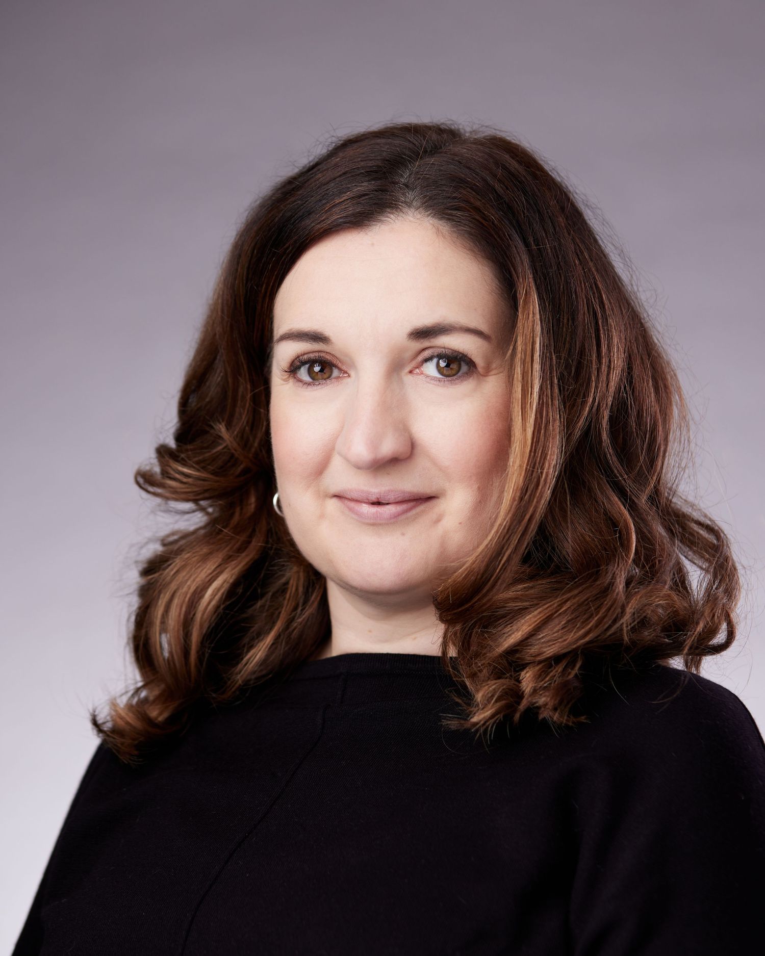 Warm Cardiff business headshot; woman with a gentle, inviting smile and approachable professional gaze.