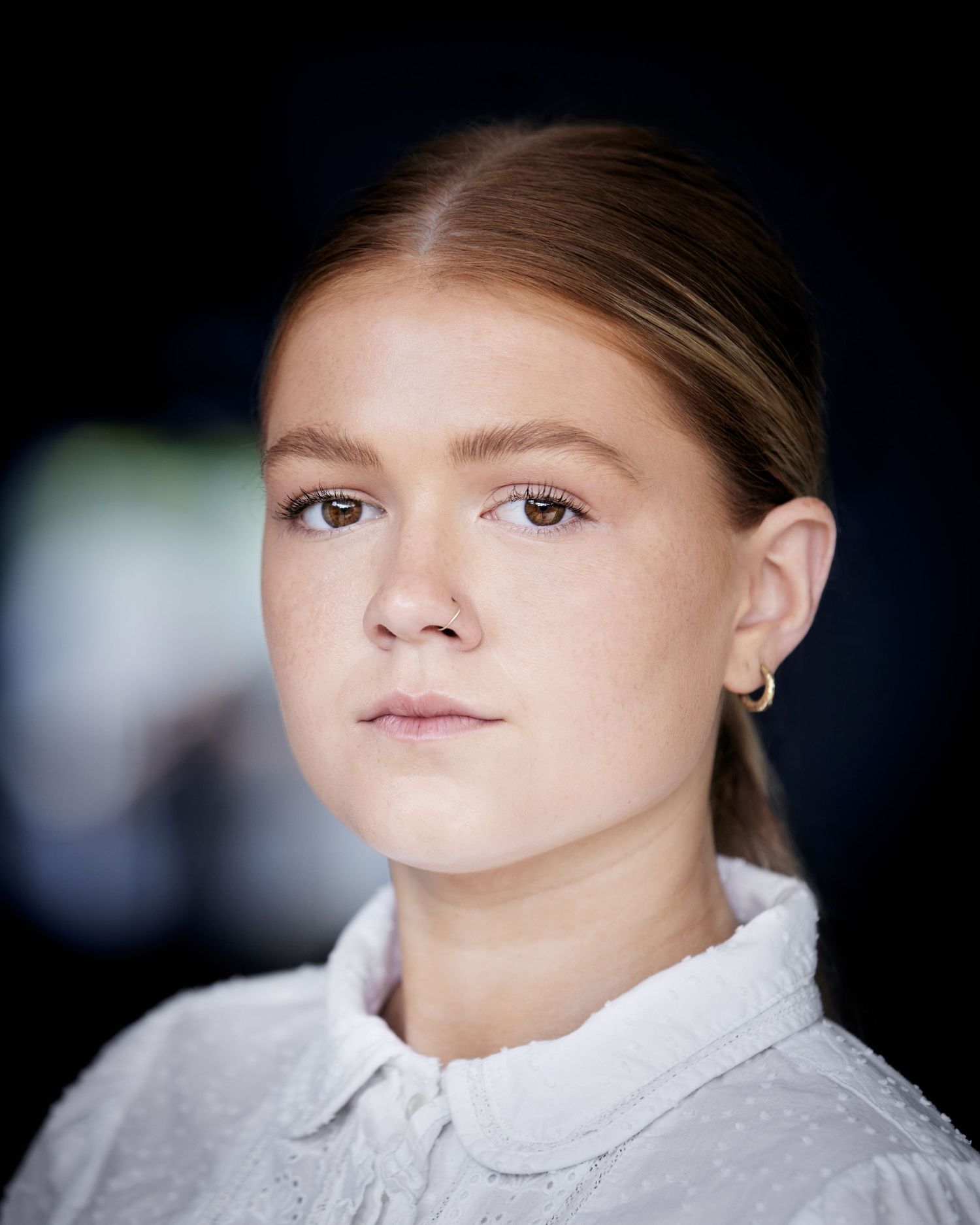 Period headshot; timeless gaze with soft-focus Cardiff natural background.