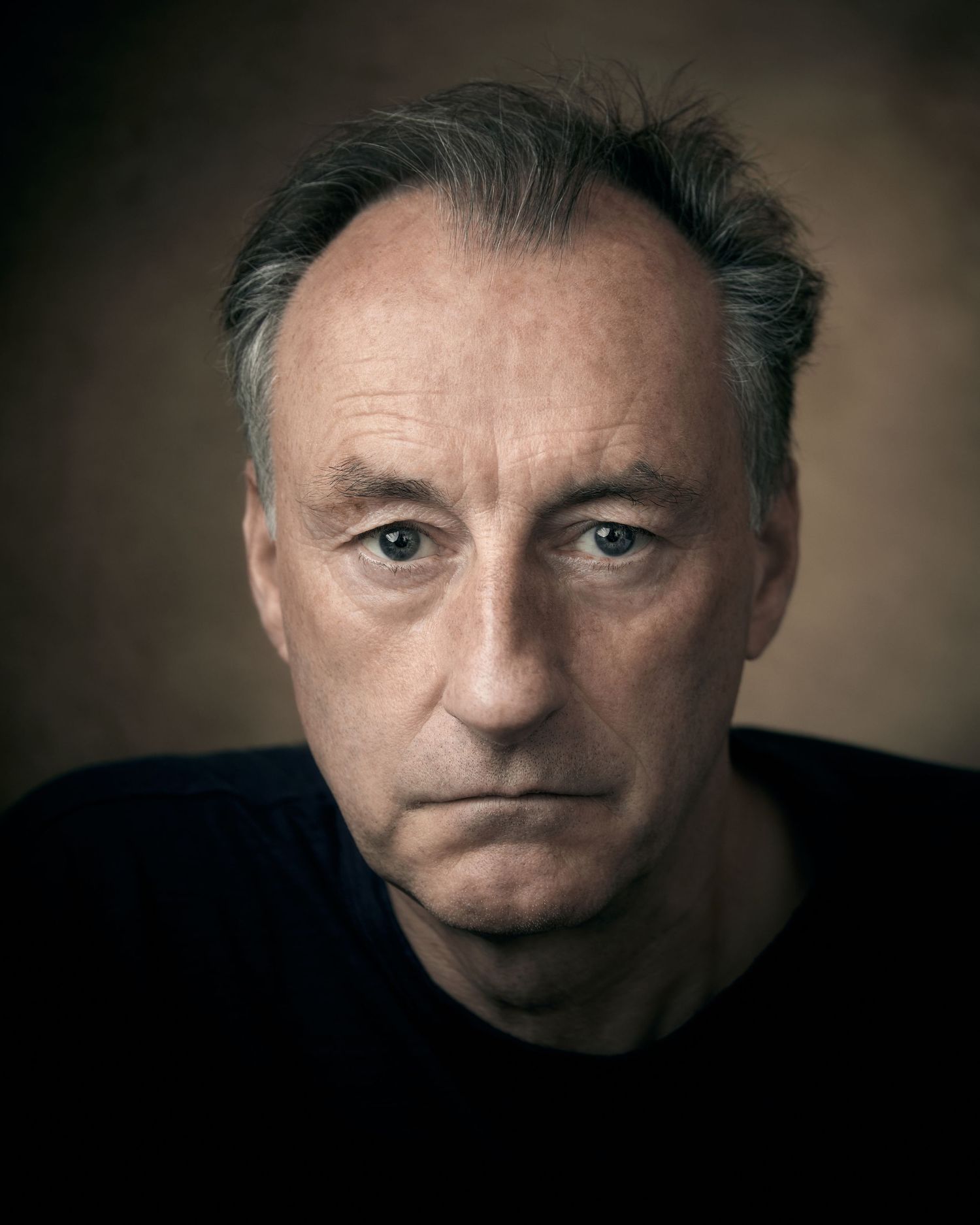 Striking character headshot; man with a cold, direct stare against a brown canvas backdrop.