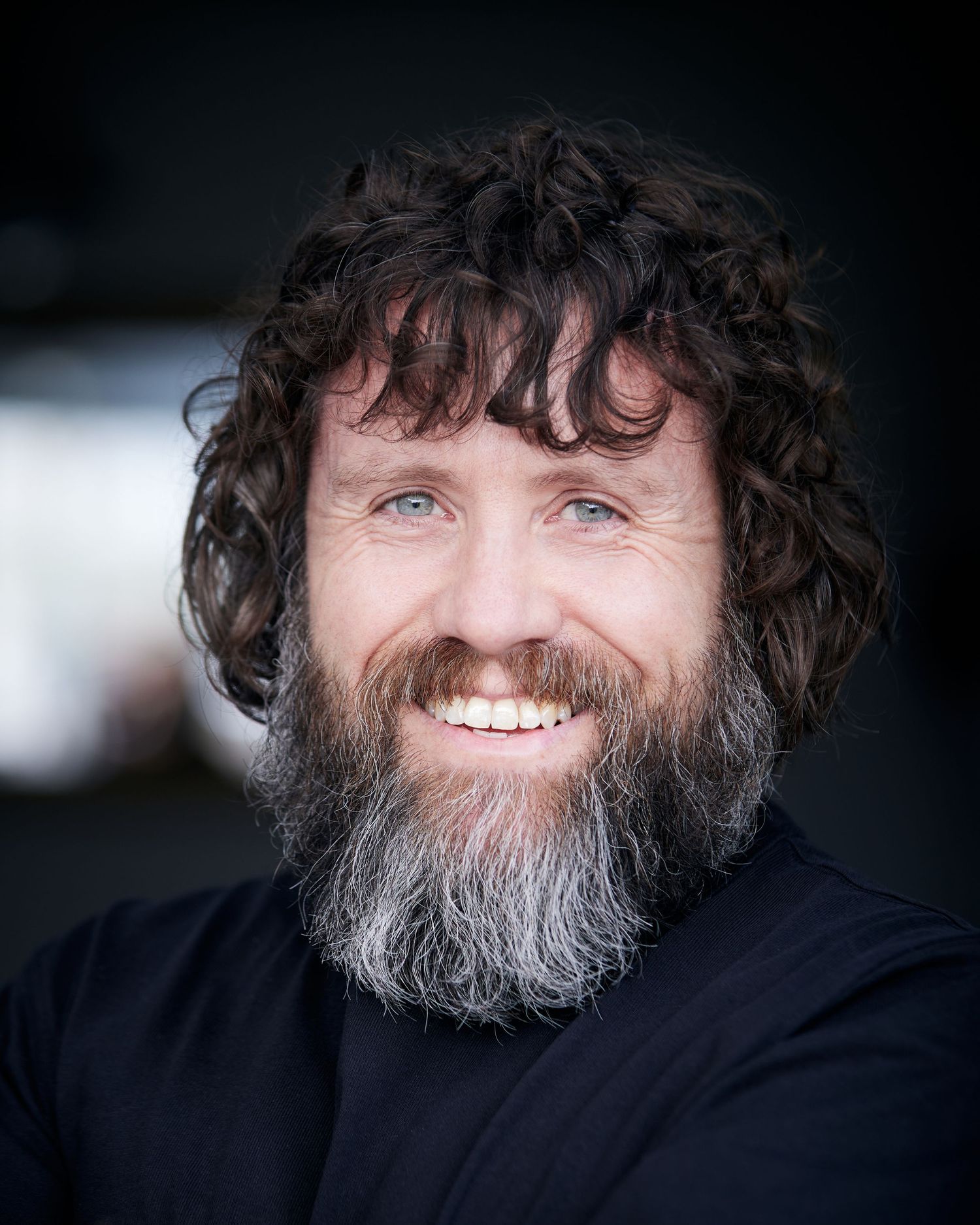 Kind natural light portrait; actor with a warm, genuine smile.