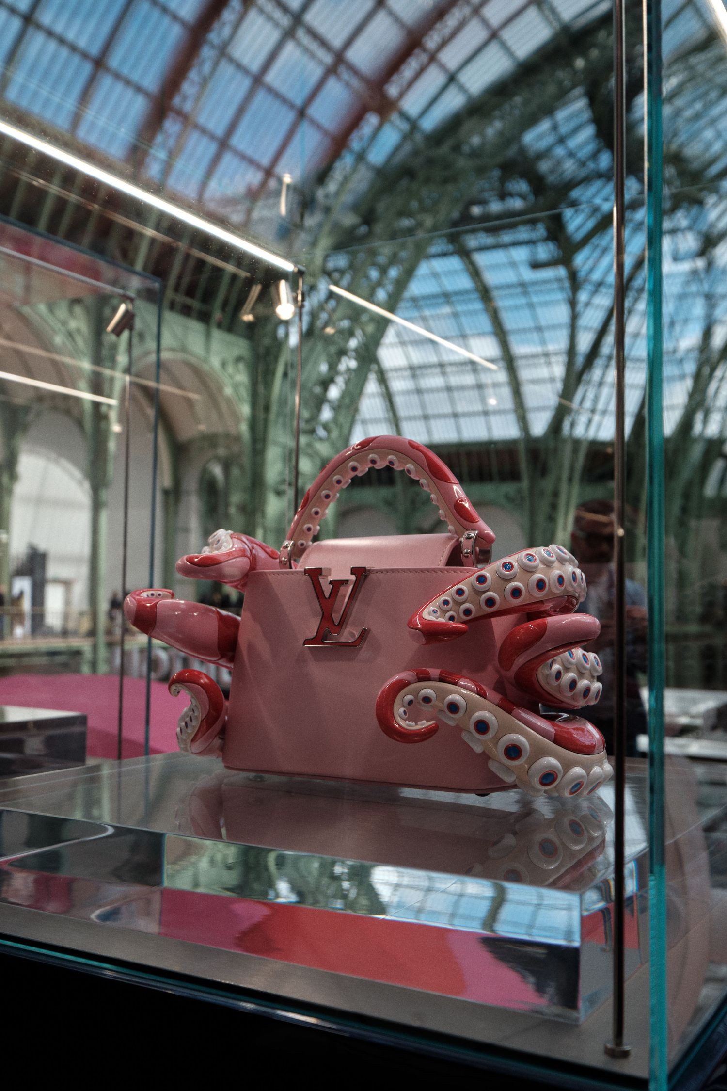 Pink Louis Vuitton octopus-shaped handbag sculpture displayed in glass case.