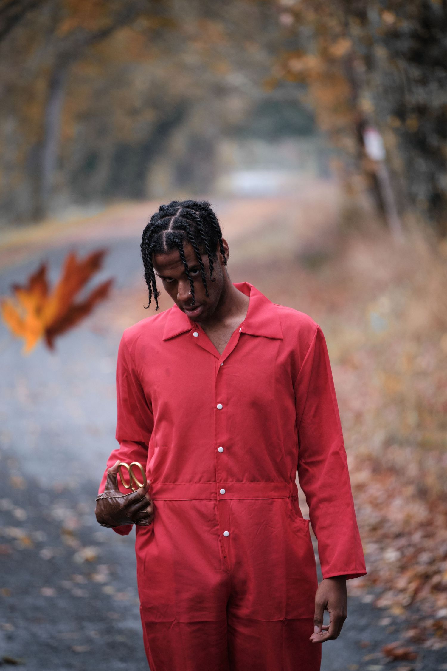 Person in bright red jumpsuit walking through autumn forest setting.