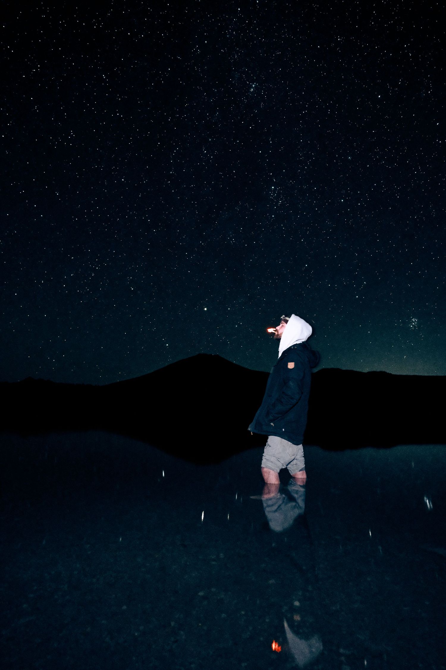 man standing under the stars smoking a cigarette.