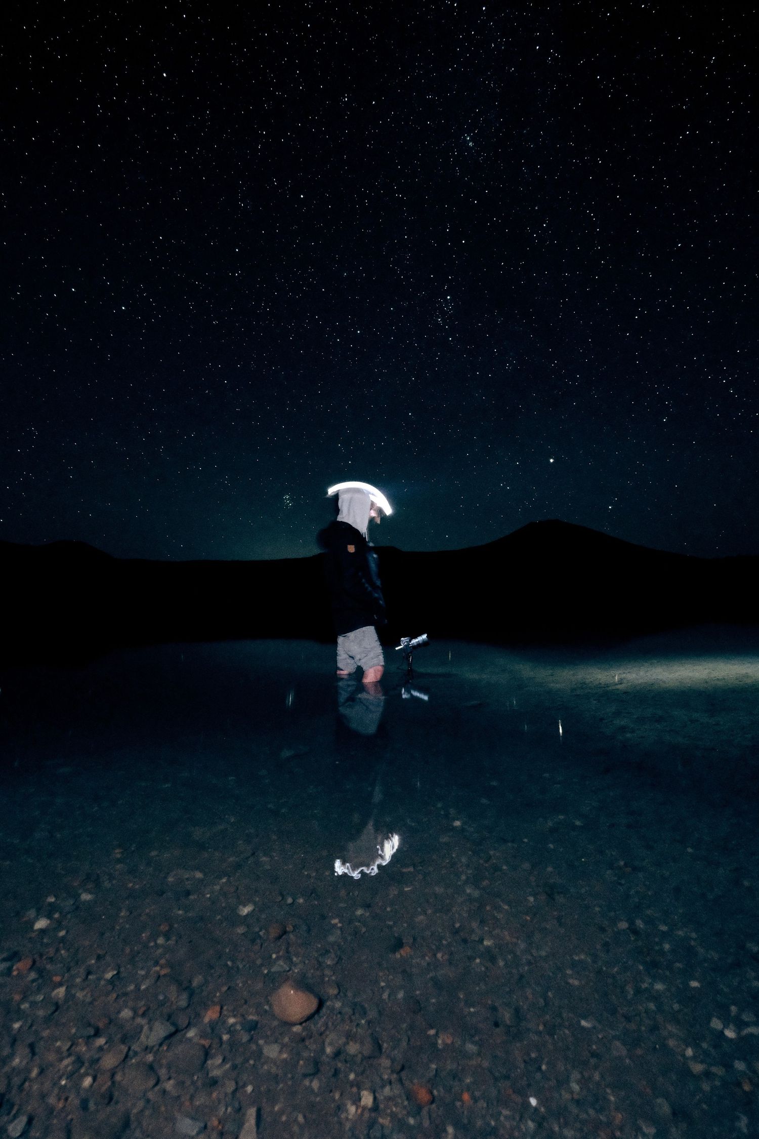 Light painting creates ethereal effects on a rocky terrain under a starry night sky.