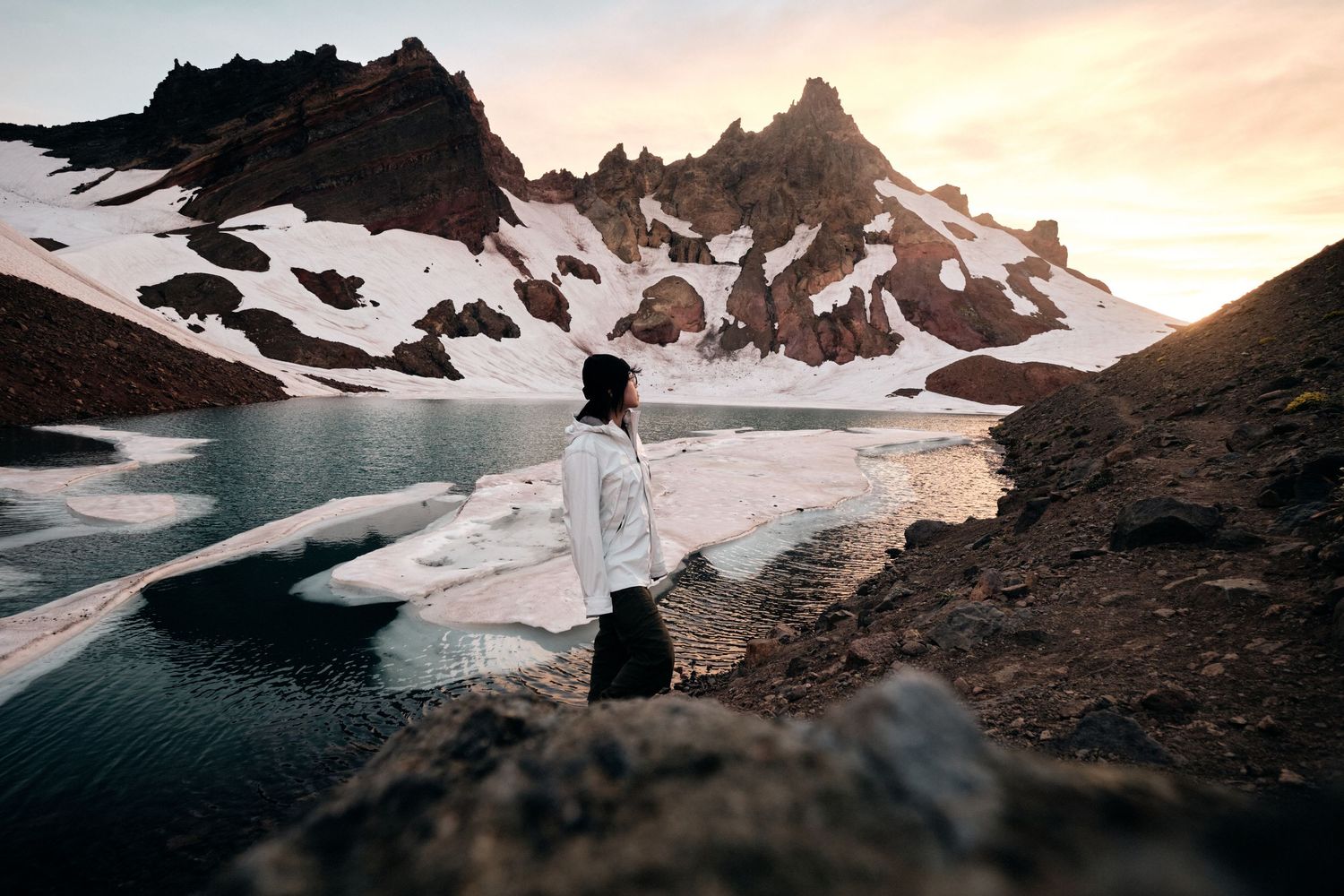 Dramatic mountain landscape with snow and rocky terrain at sunset.