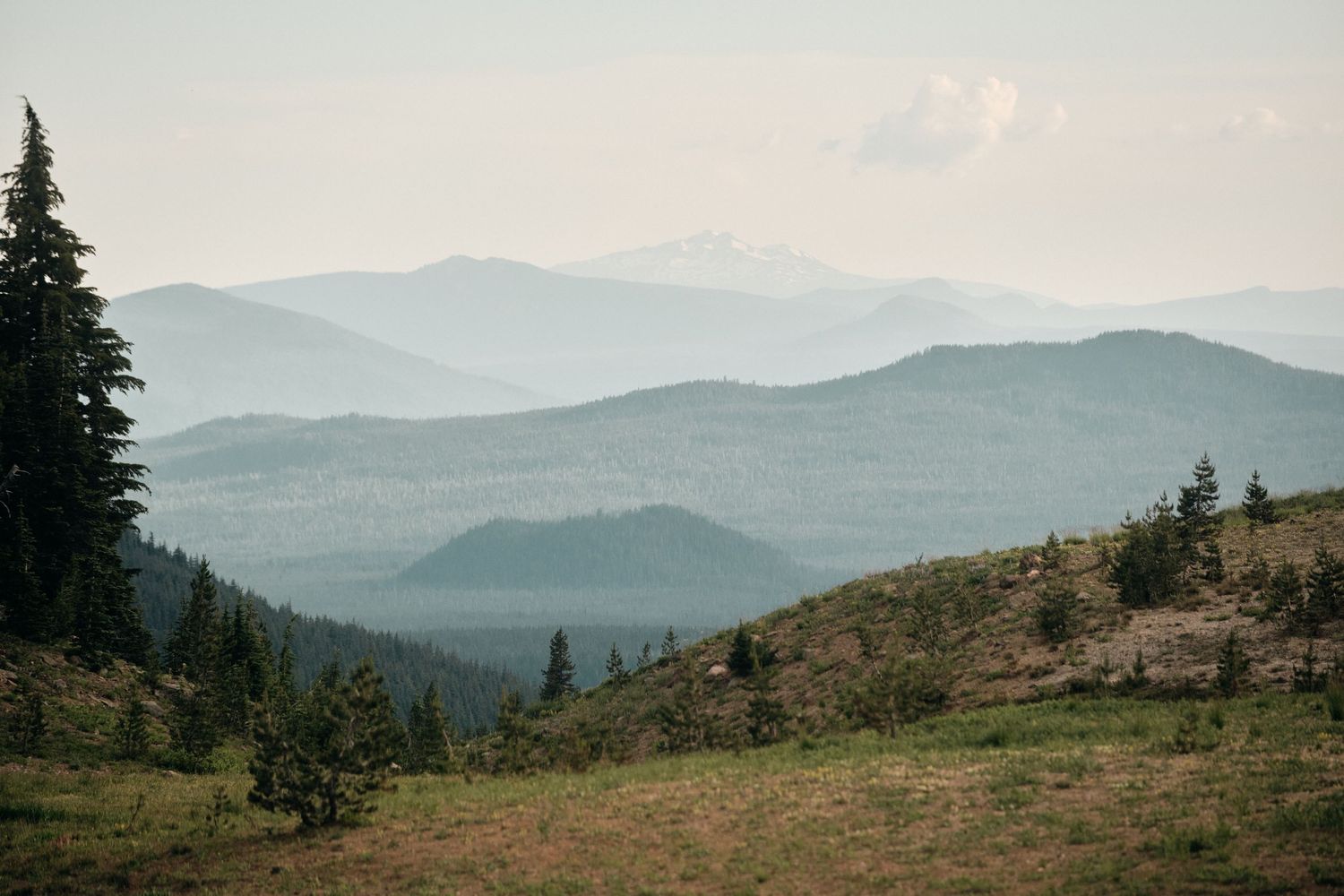 Rolling mountain ranges fade into the distance under hazy sky.
