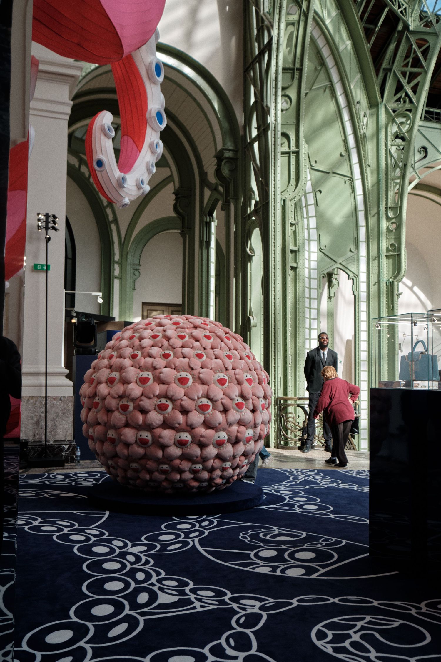 Large pink sculptural installation under ornate glass and metal ceiling architecture.