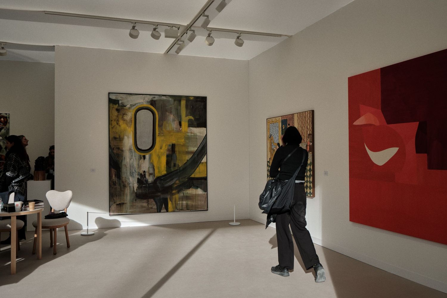 Modern art gallery interior showing various abstract paintings mounted on white walls.