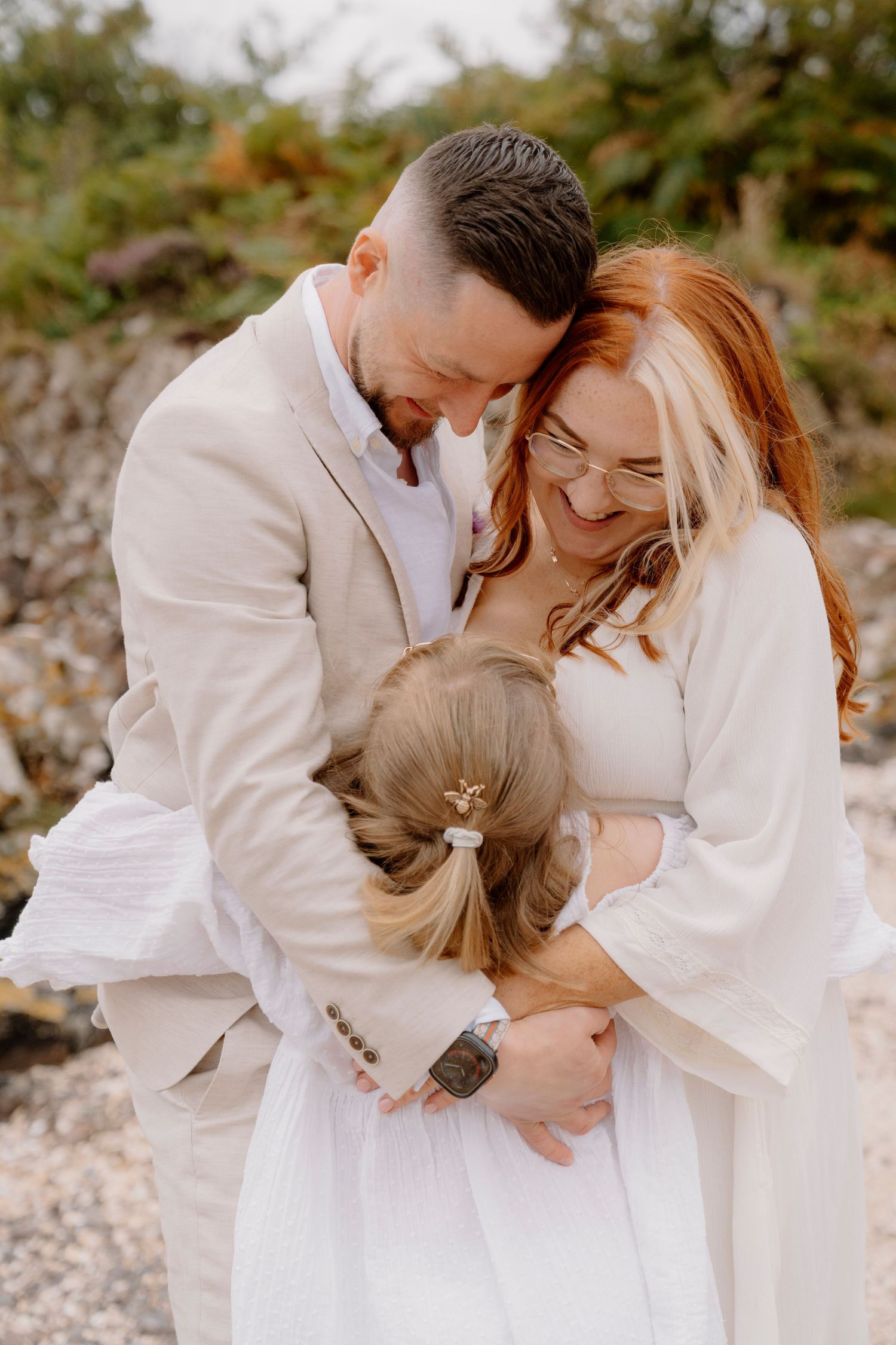 Three people share an intimate moment of laughter during outdoor photo session.