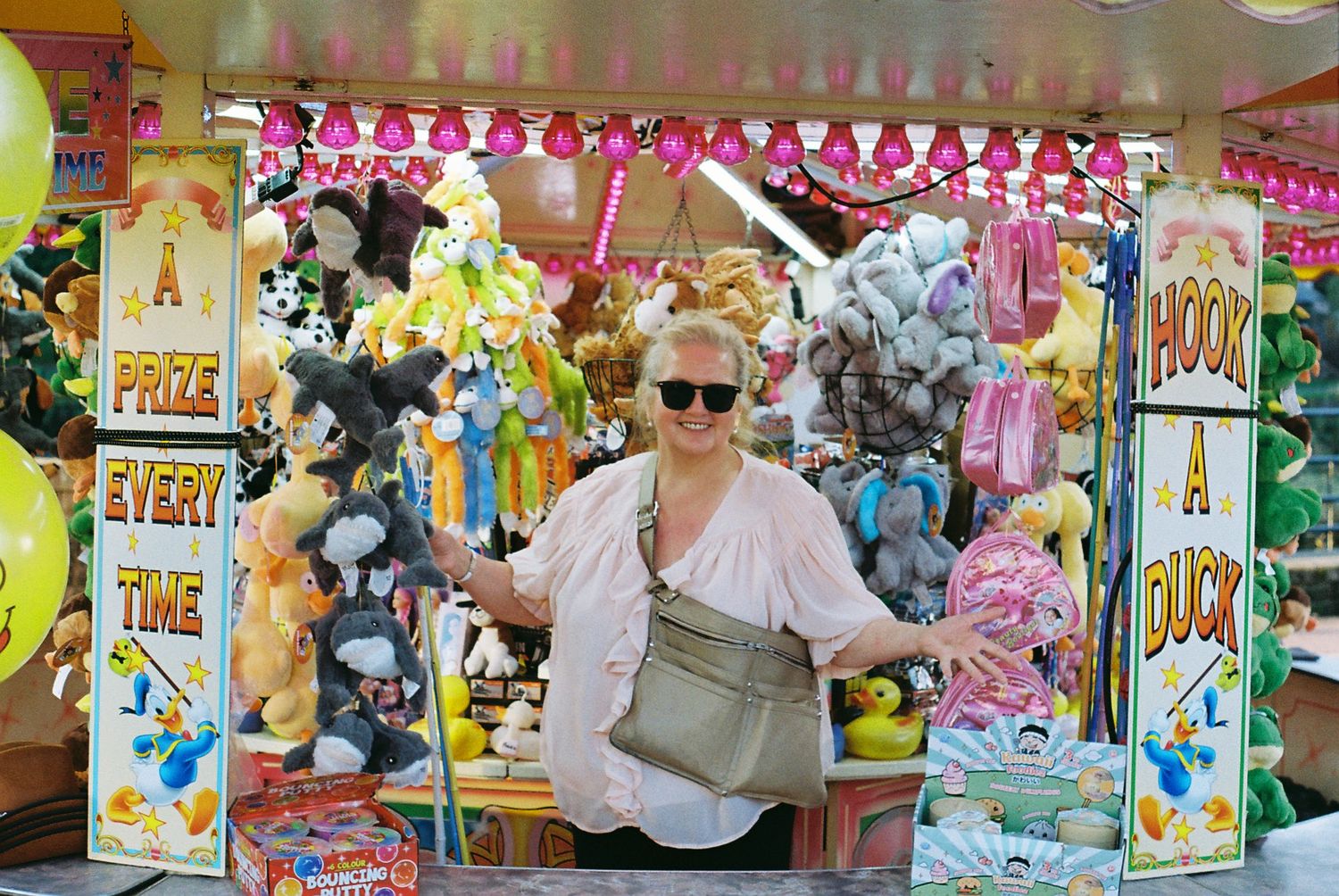 A colorful carnival game booth filled with plush toys and stuffed animals as prizes at an amusement park.