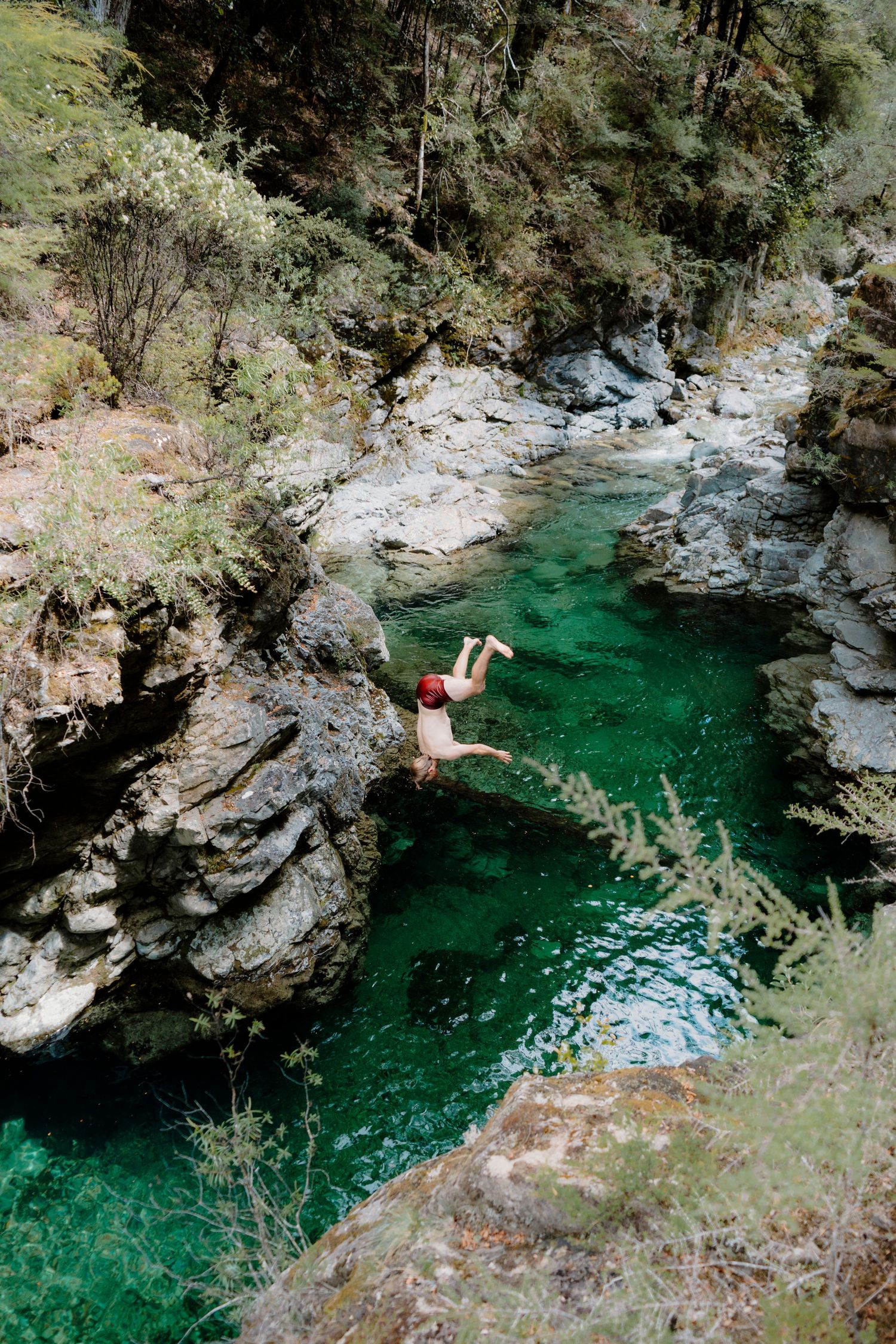 Emerald green swimming hole nestled between rocky cliffs in a scenic mountain gorge shows pristine natural beauty.
