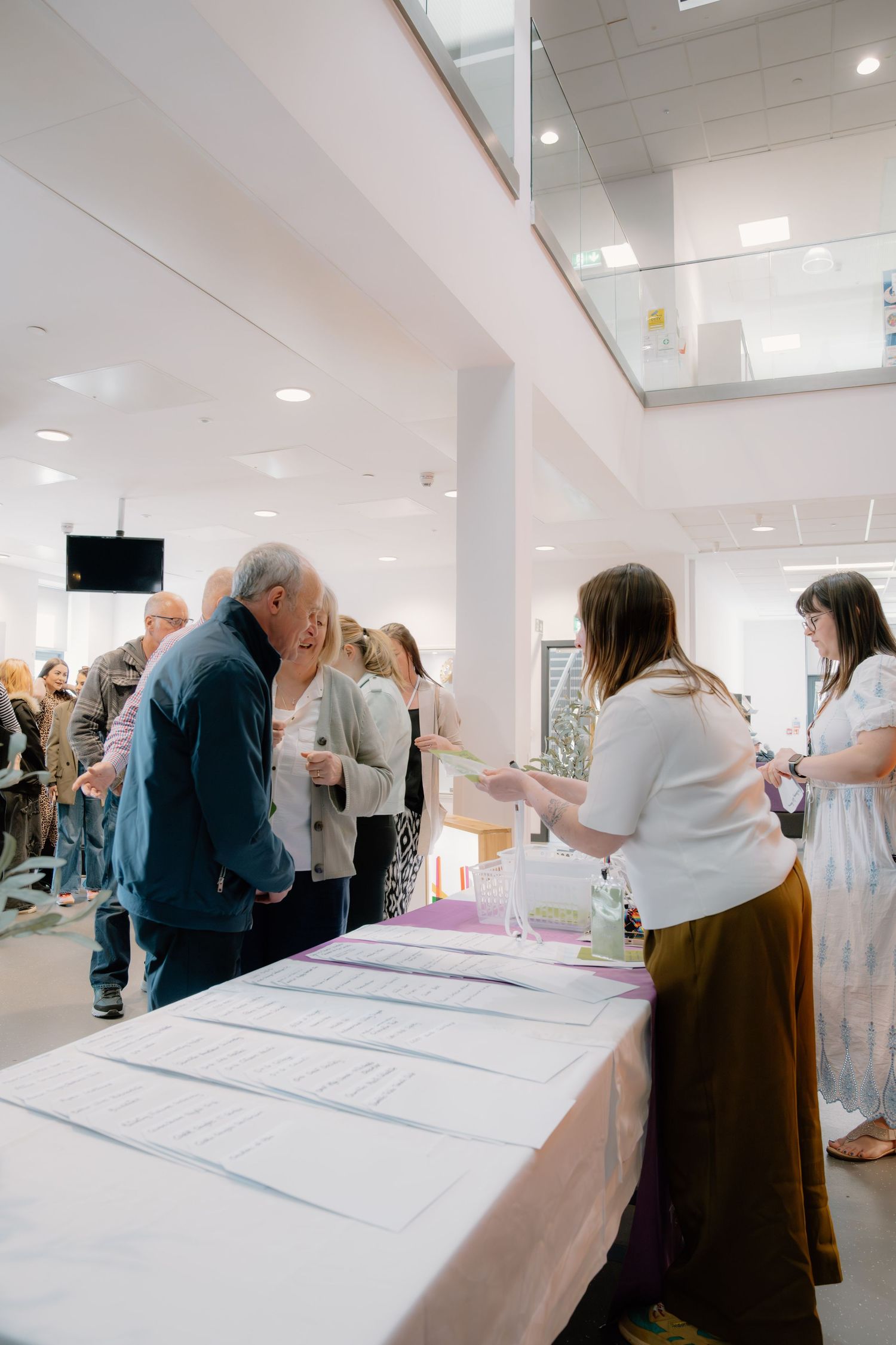 People registering at a welcome table during an indoor event in a bright modern venue.