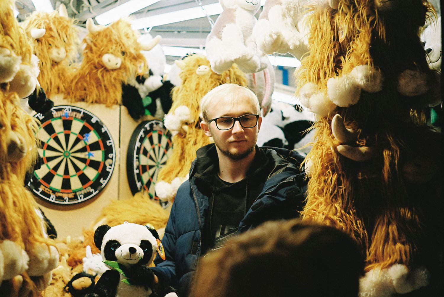 A group of people wearing straw costumes participate in a traditional folk festival with dartboards visible in background.