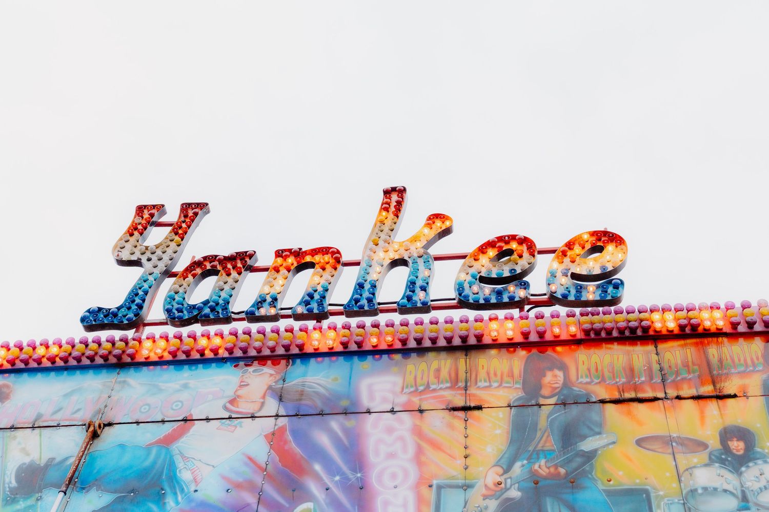 A collage of carnival rides and amusement park attractions with bright neon lights against a dark sky.