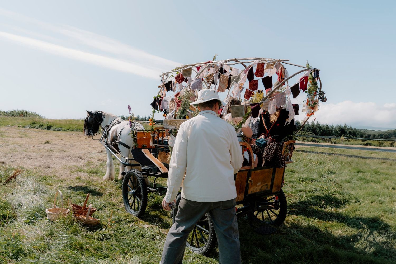 Rustic wooden wagon decorated with colorful flags stands in an open field.