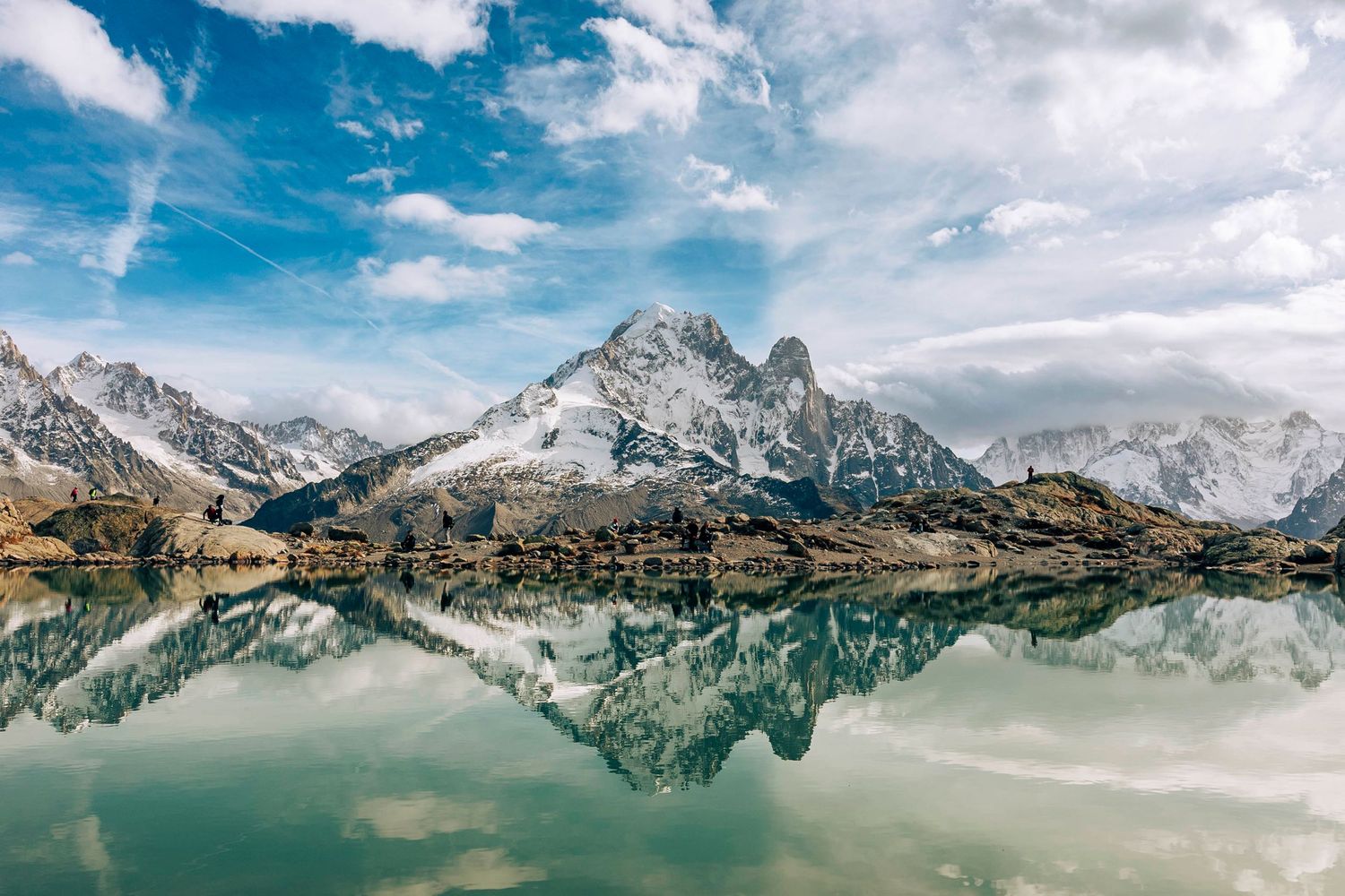 Panoramic view of snow-capped mountains reflecting in a pristine alpine lake.