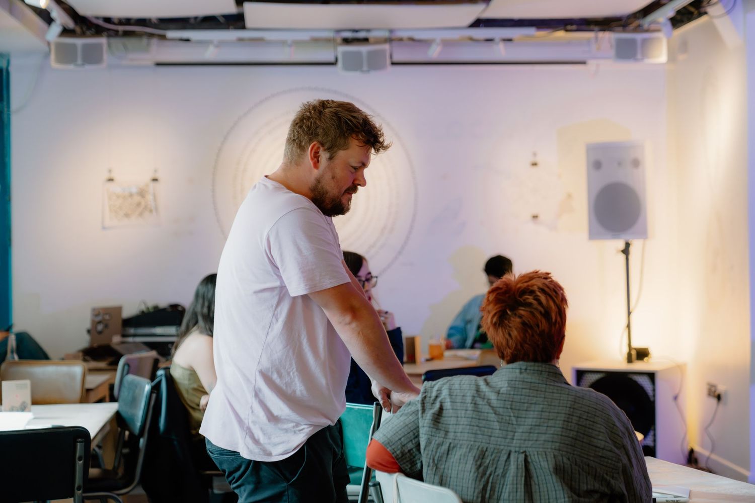 Two people collaborating in a modern creative studio space with white walls and audio equipment.