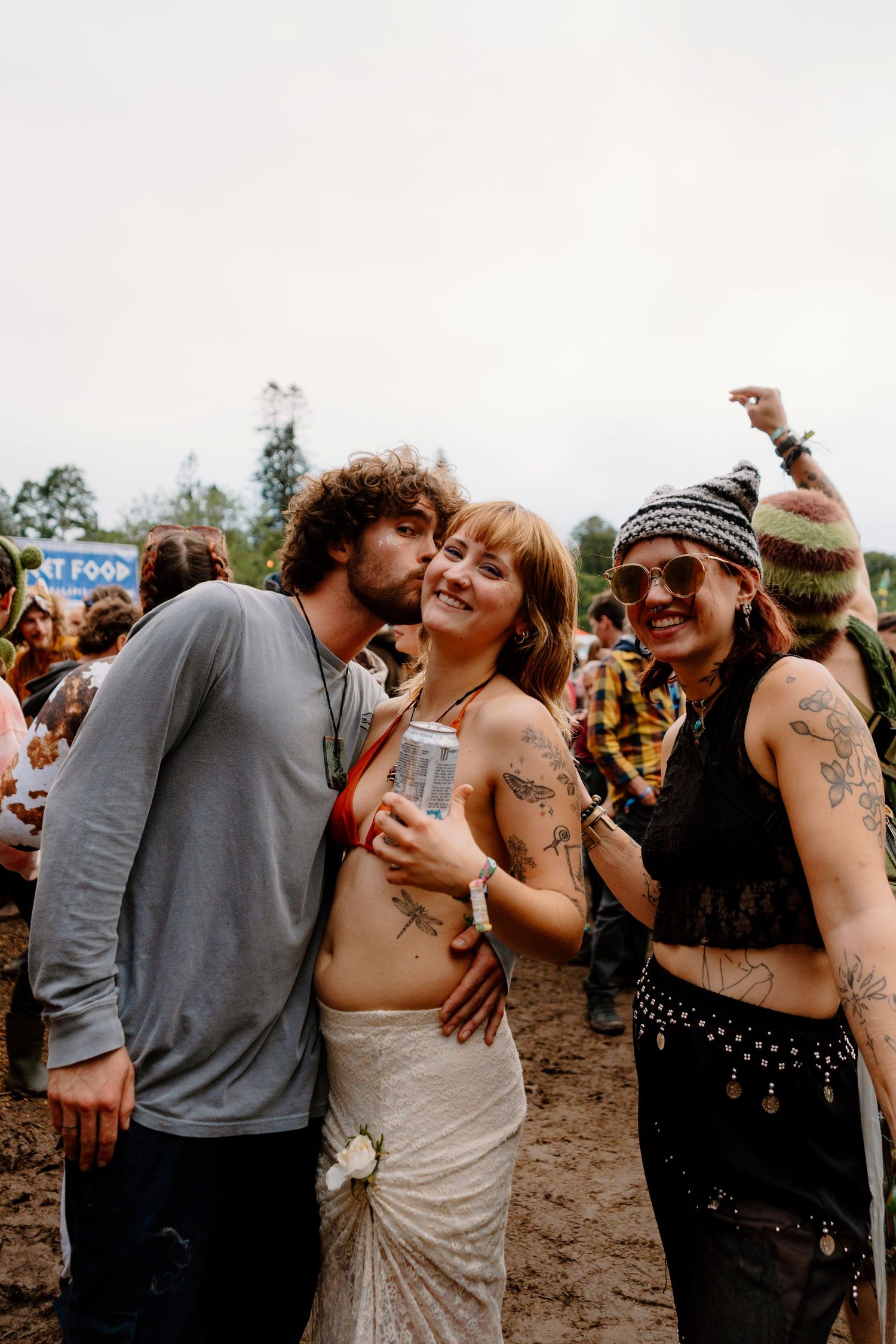 Festival-goers dancing and embracing at an outdoor music event on a sunny day.