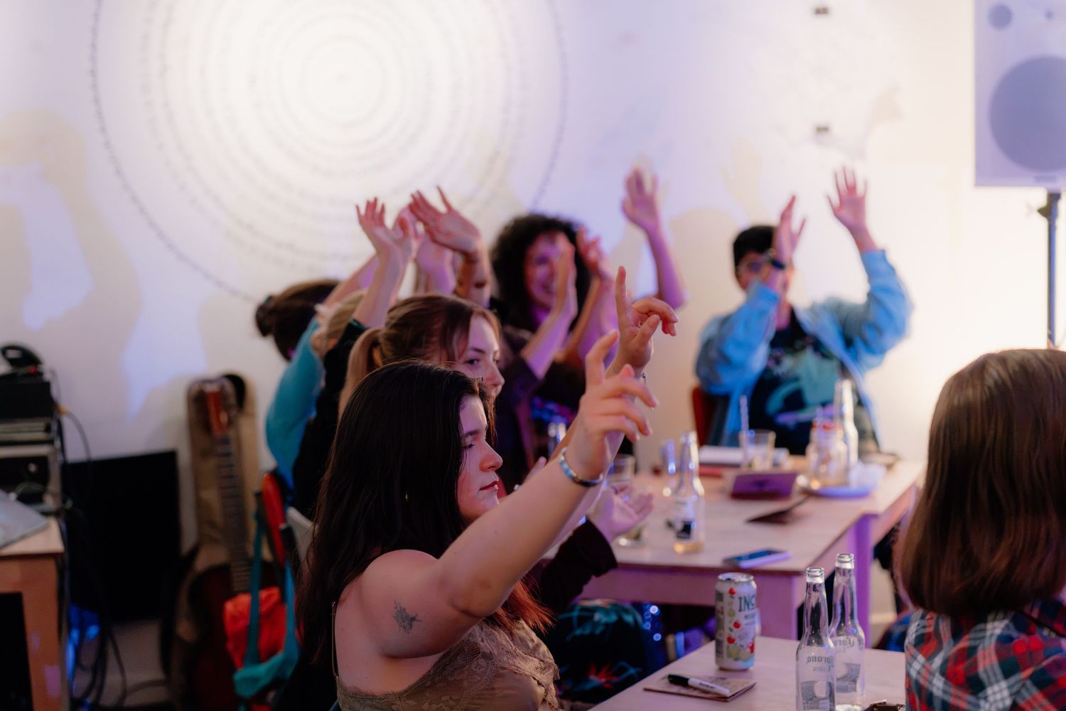 Group of women dancing with hands raised at a lively indoor party with colorful lights and music.