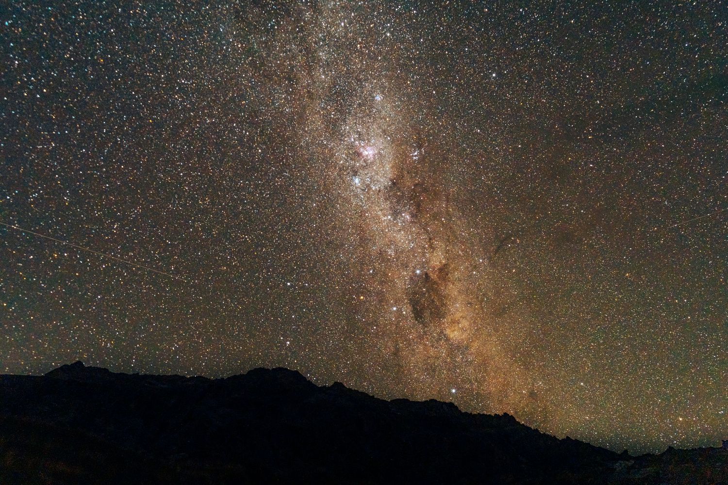 Stunning view of the Milky Way galaxy stretching across a dark night sky above silhouetted mountain peaks.