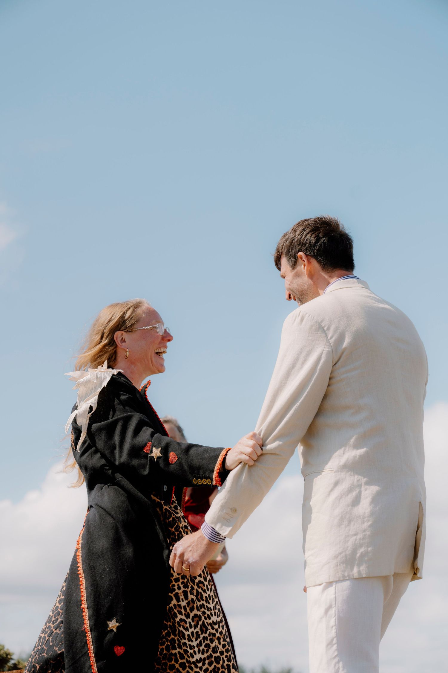 Couple holding hands and walking together against blue sky.