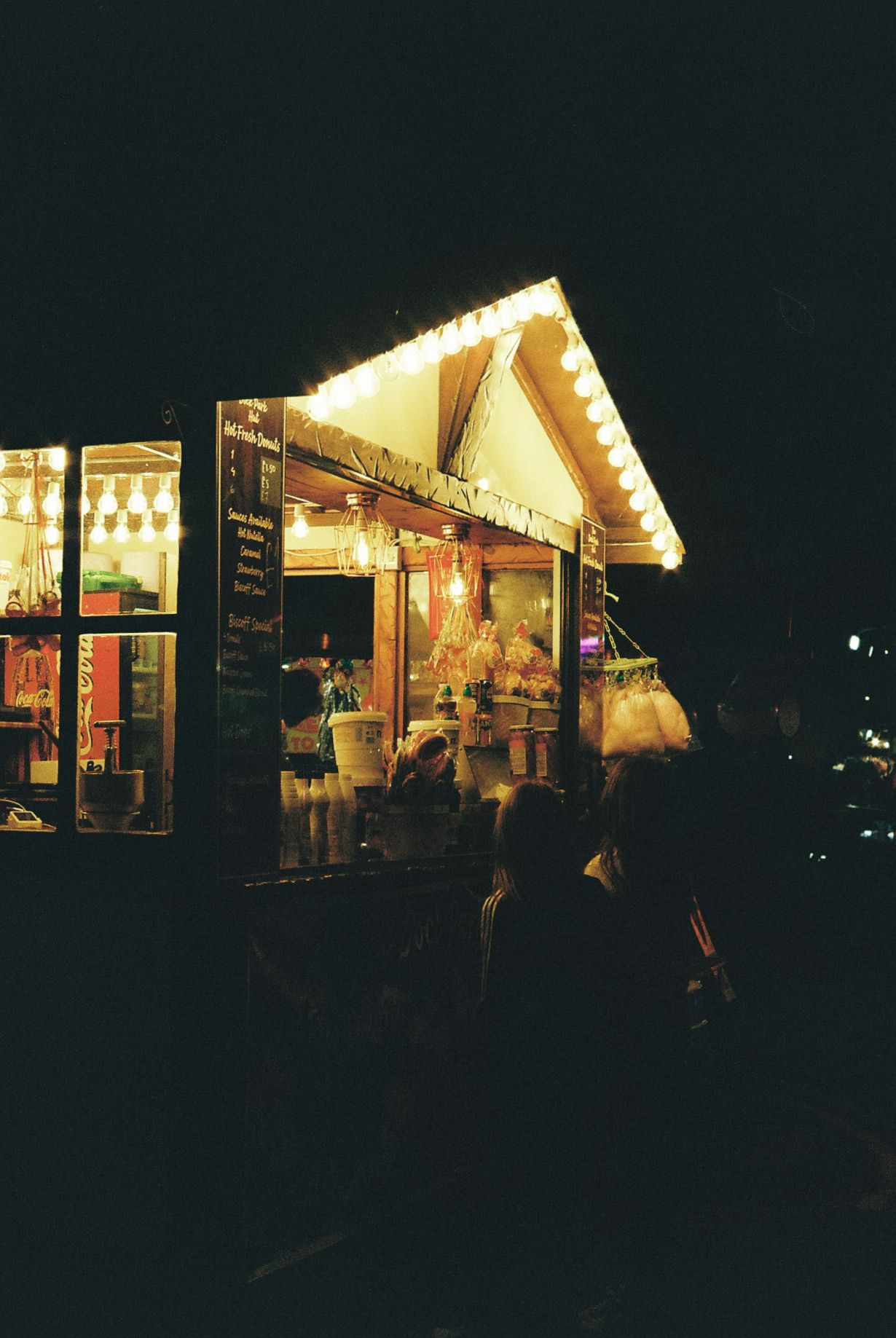 Illuminated small retail shops and storefronts glowing warmly against the dark night sky.