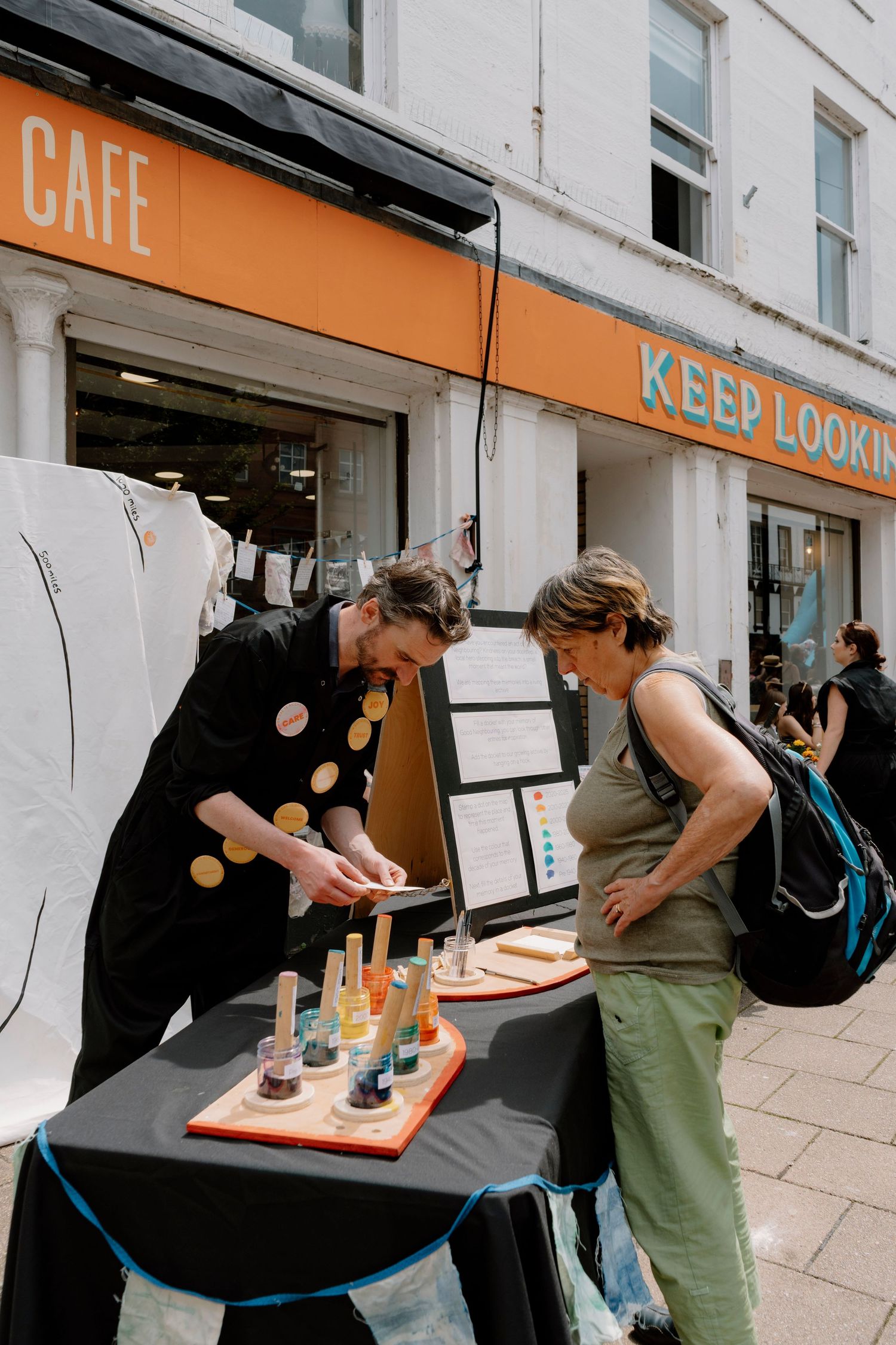 Staff preparing food and drinks at an outdoor cafe counter.