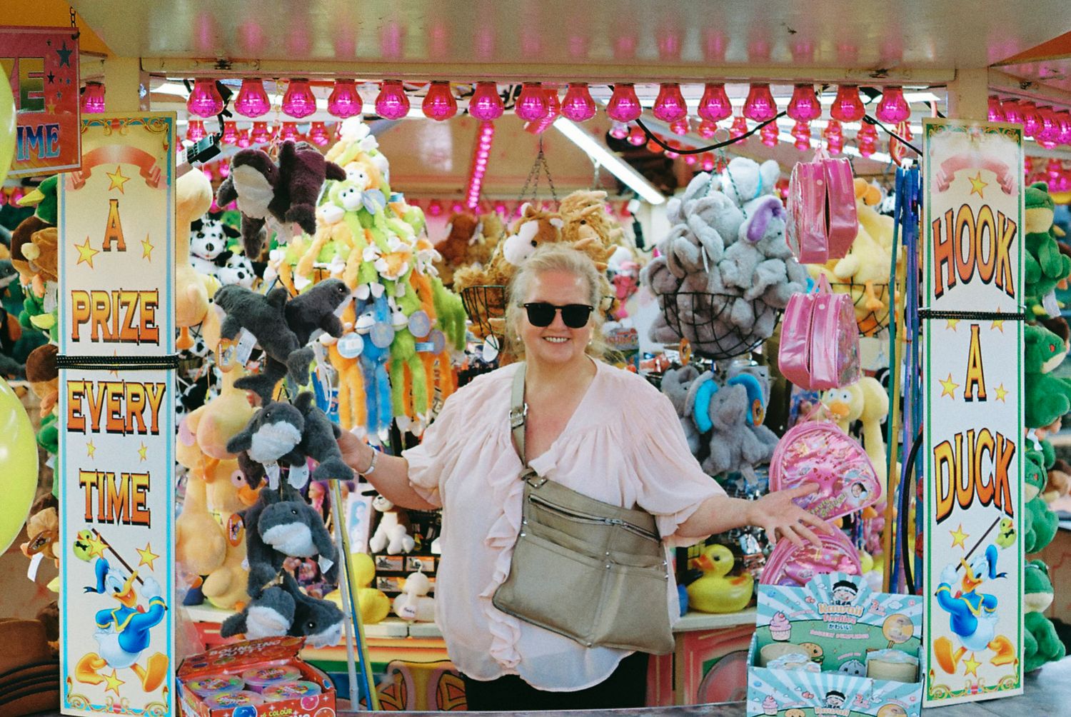Colorful carnival game booth displays filled with plush toys and prizes at an amusement park or fair.