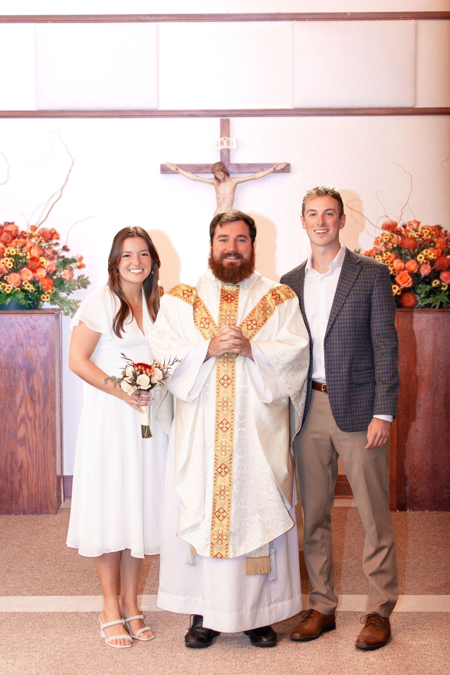 A wedding portrait with a priest in traditional gold vestments at the altar.