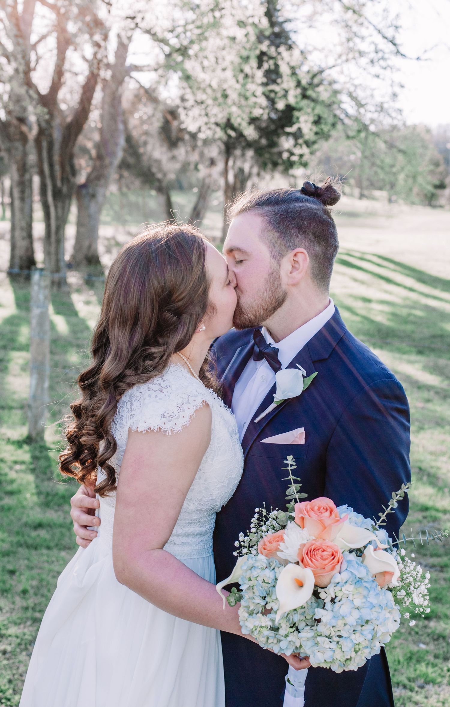 A romantic spring wedding portrait with blooming trees in the background.