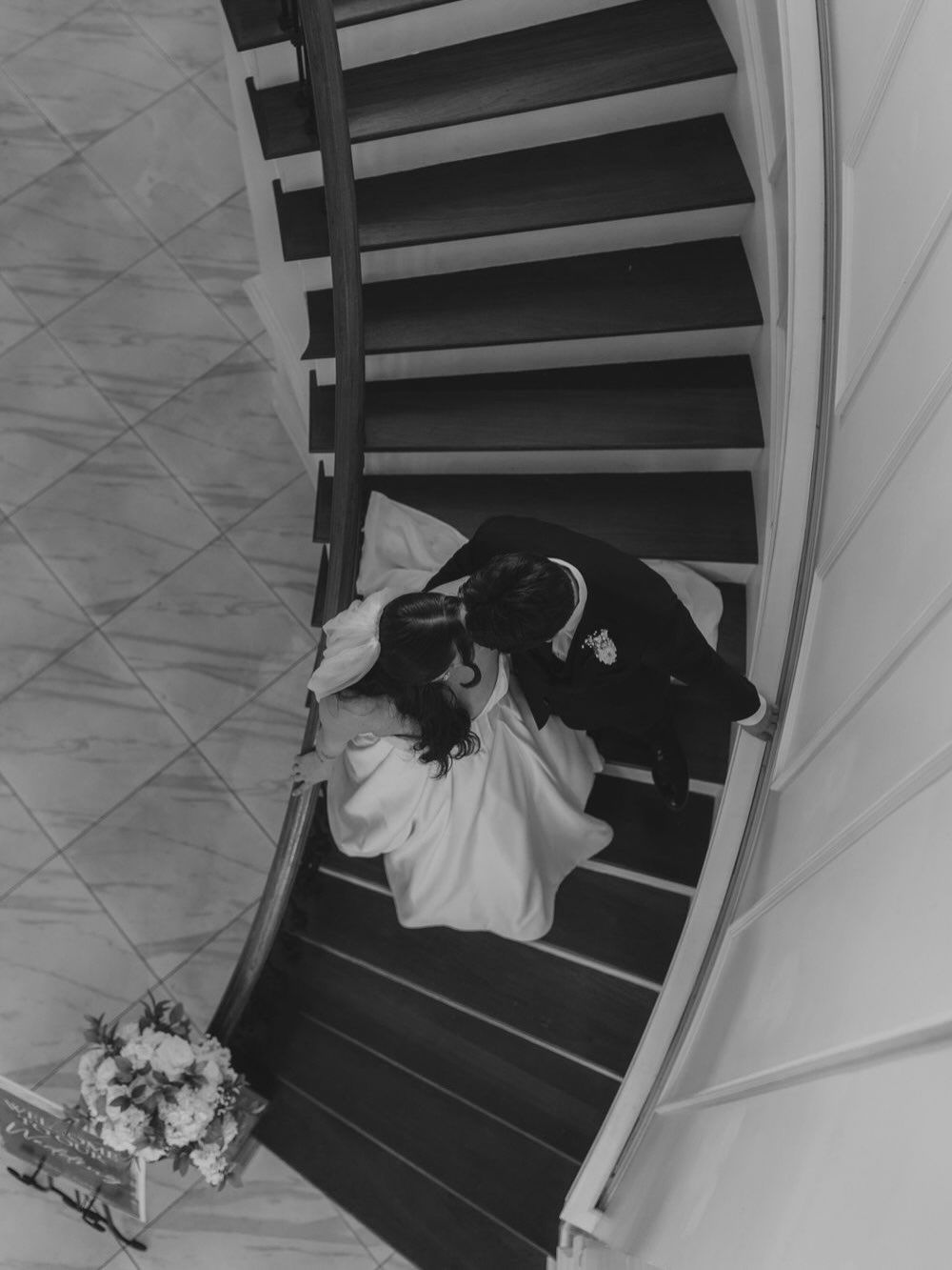 Wedding dress train cascading down elegant black staircase.