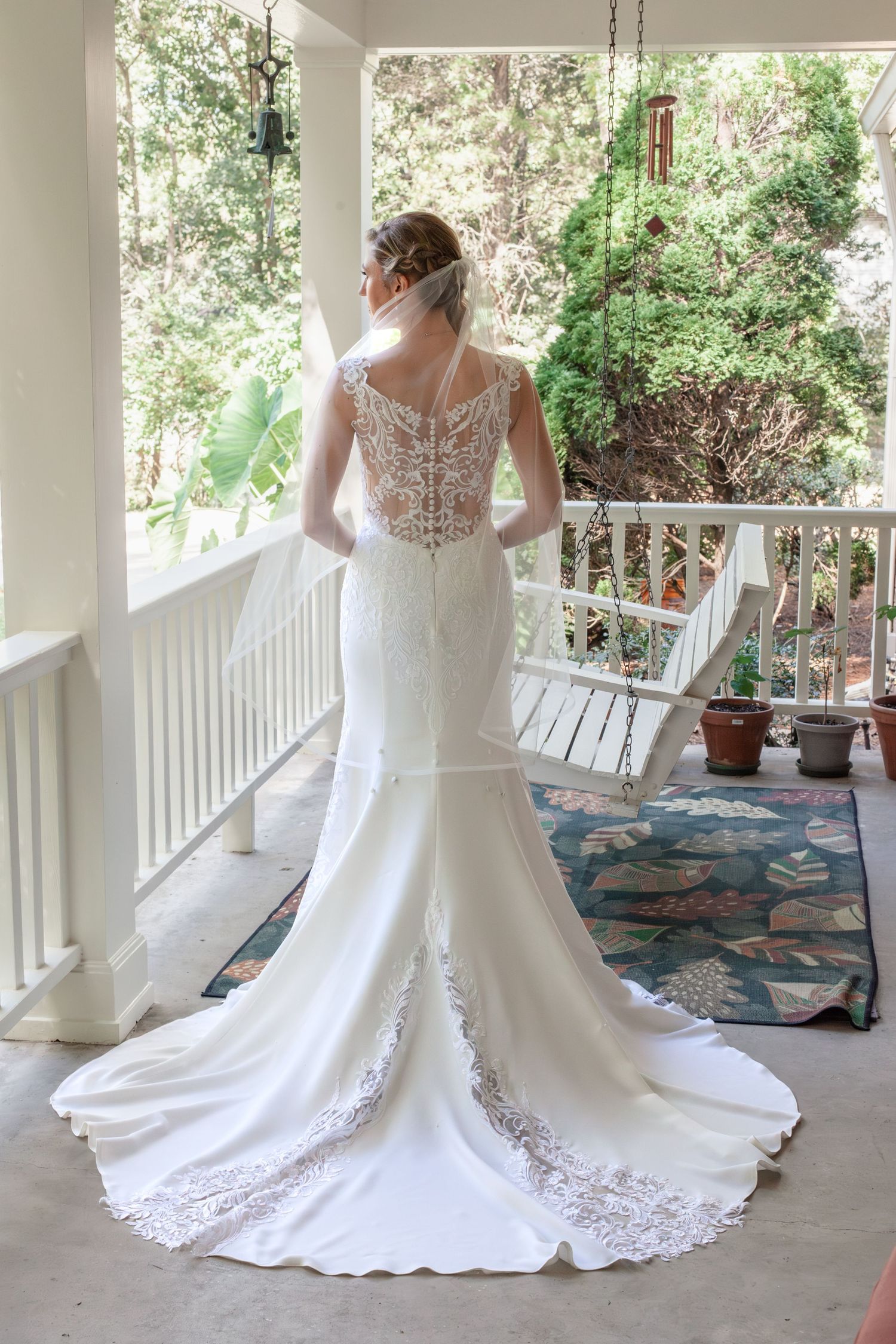 Wedding dress with detailed lace back twirls on a covered porch in multiple artistic shots.