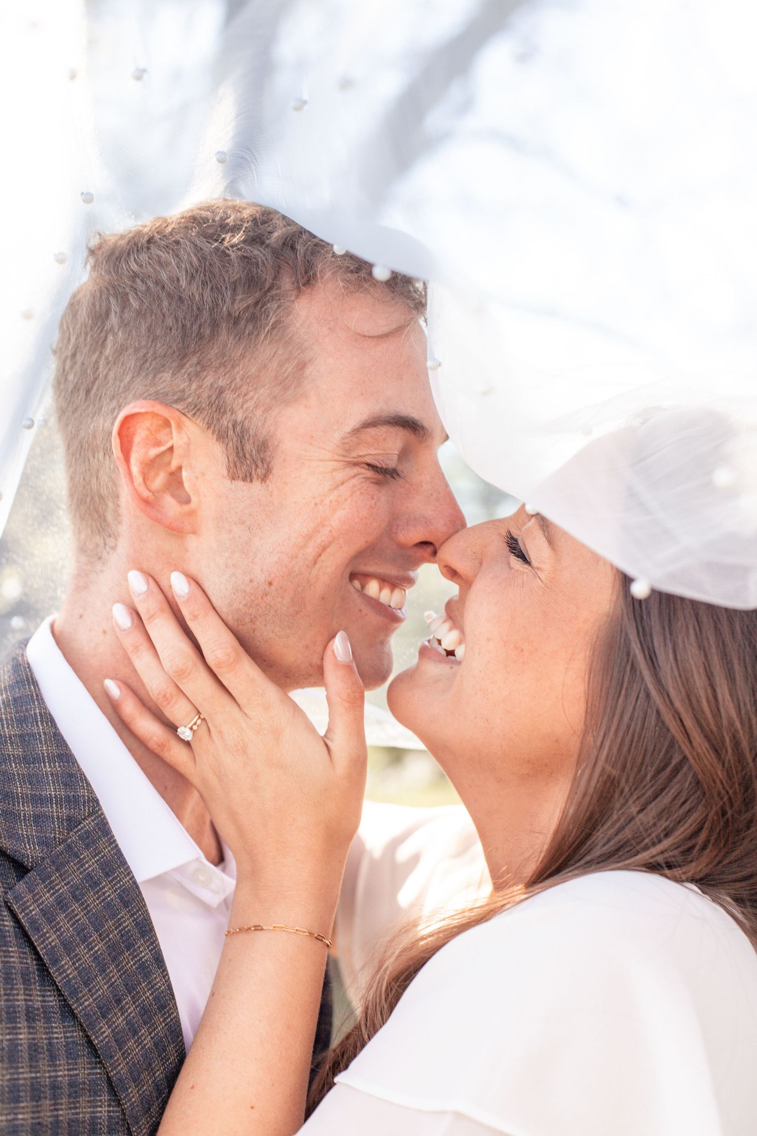 A romantic couple shares an intimate moment under a veil during their wedding photoshoot.