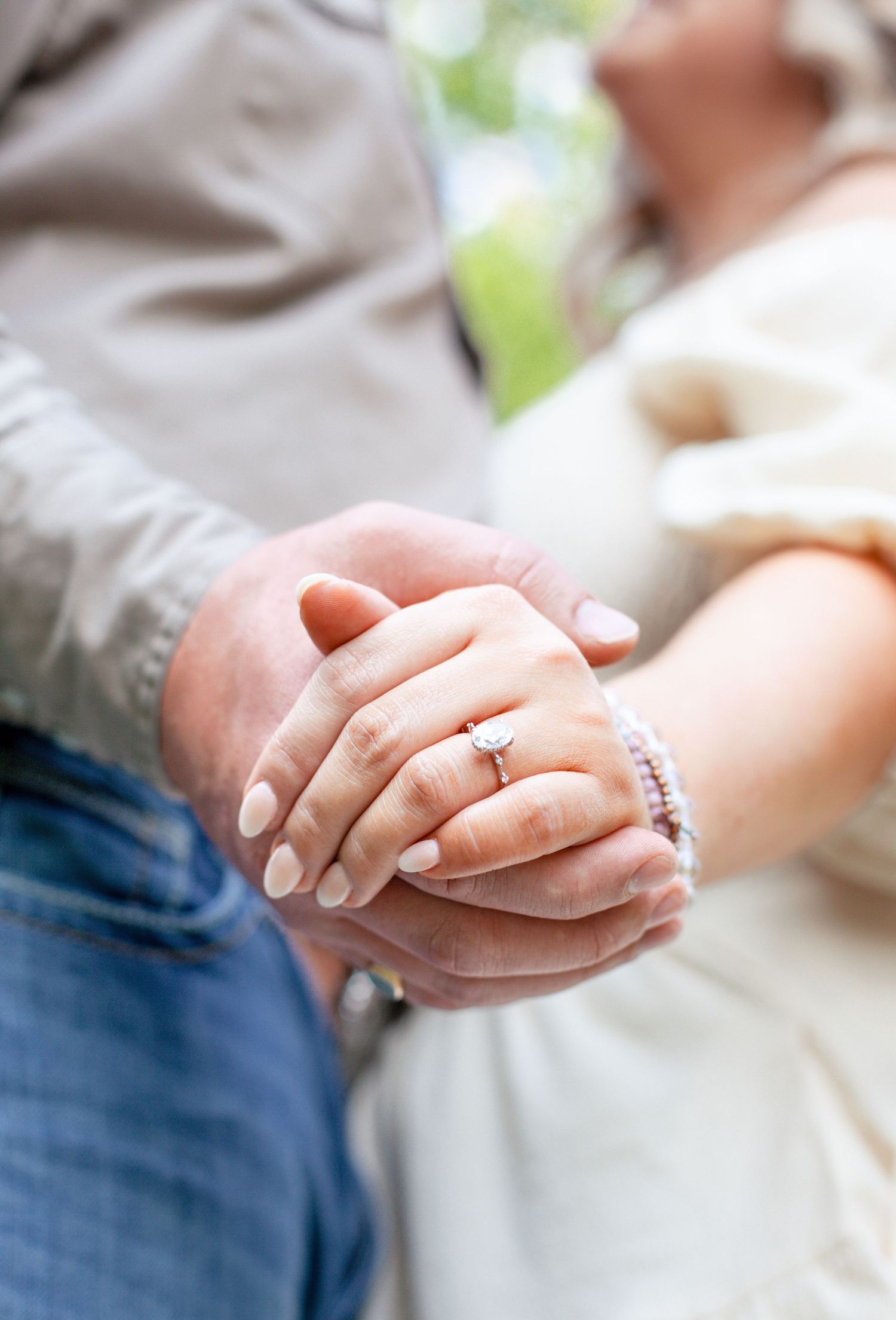 Close-up of couple's hands with wedding rings and delicate jewelry.