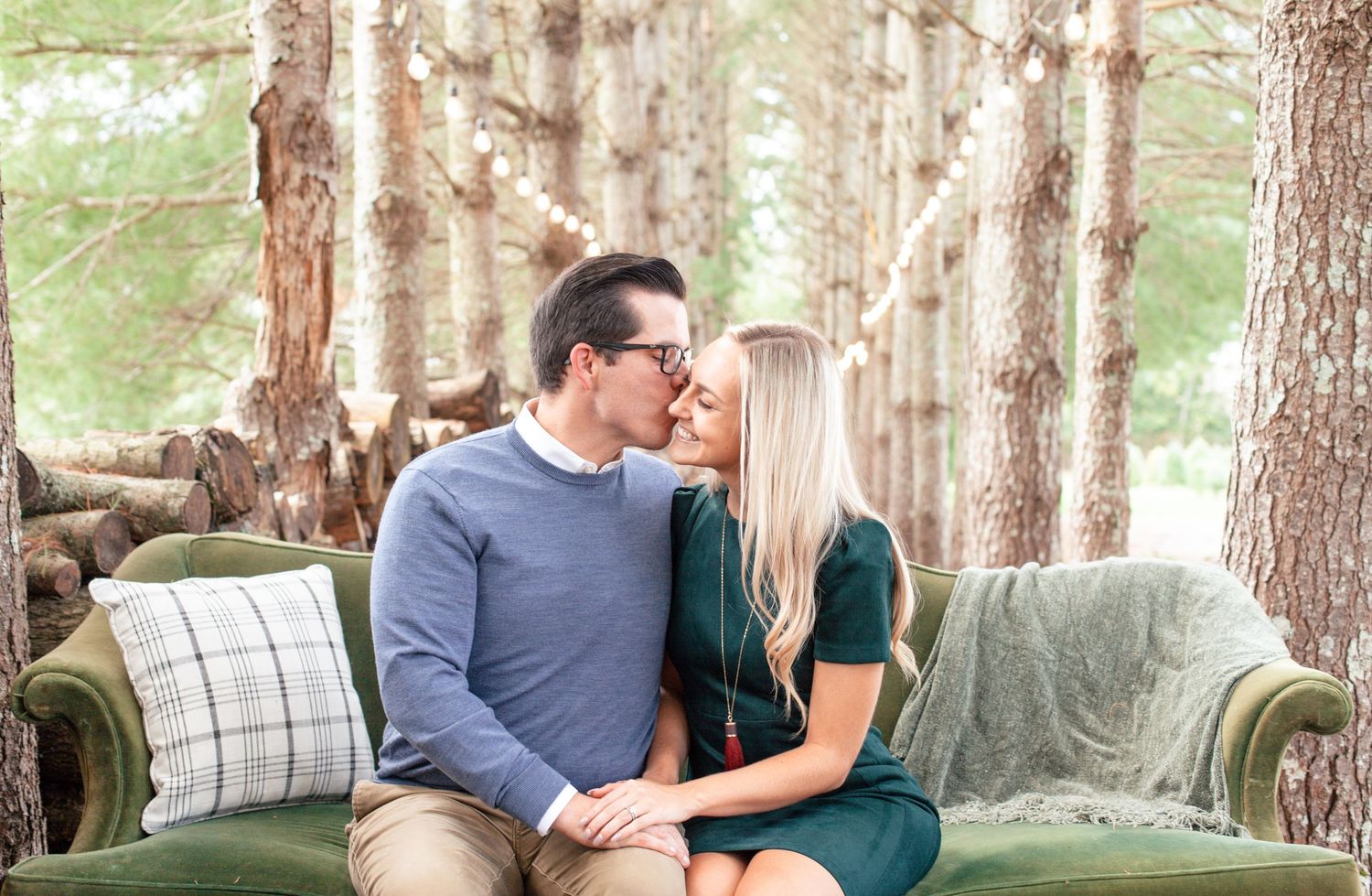 Outdoor engagement photo session in a pine forest with a vintage green velvet couch.