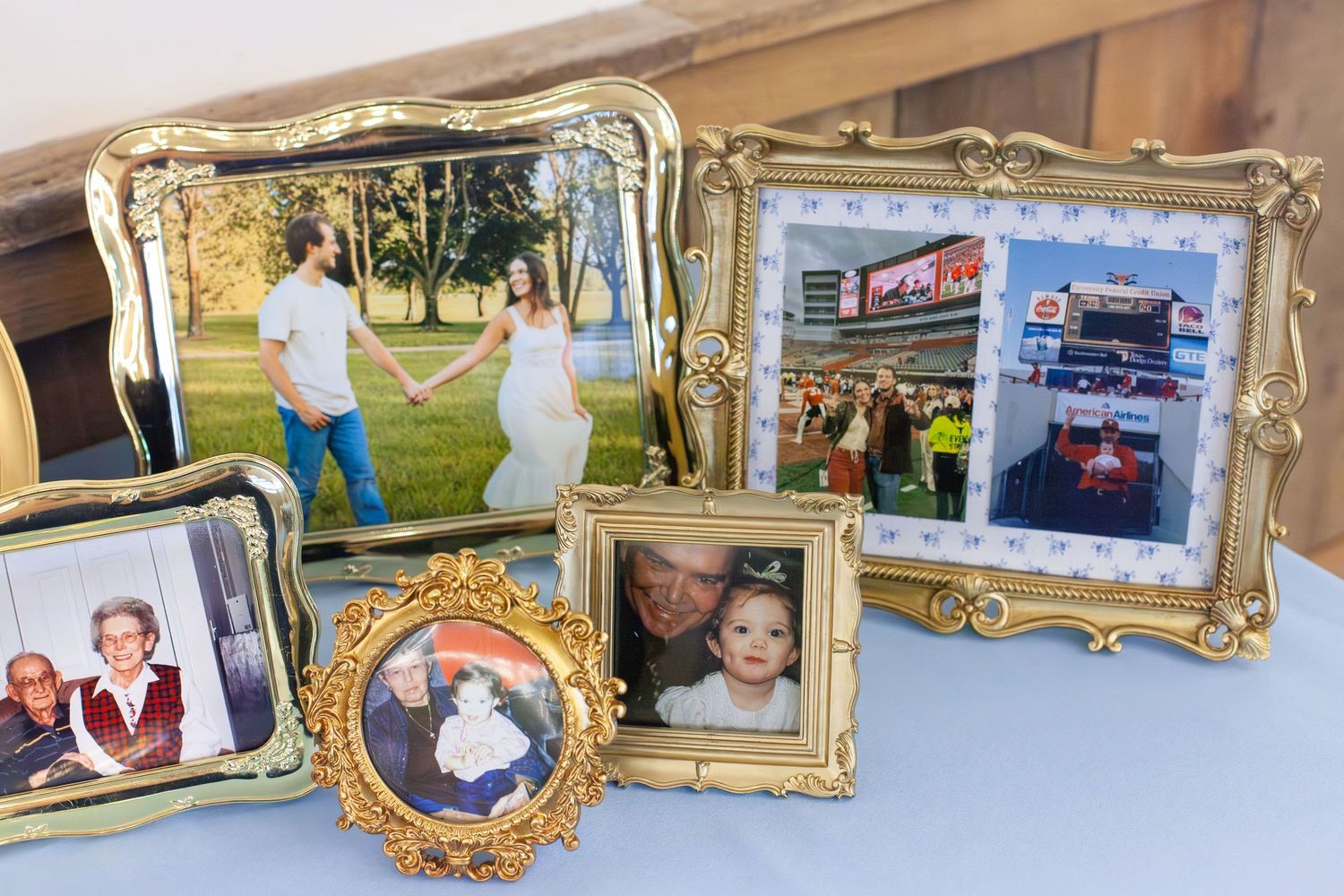 Gold ornate picture frames displaying family photos including a maternity shoot and fire truck image on a blue table.
